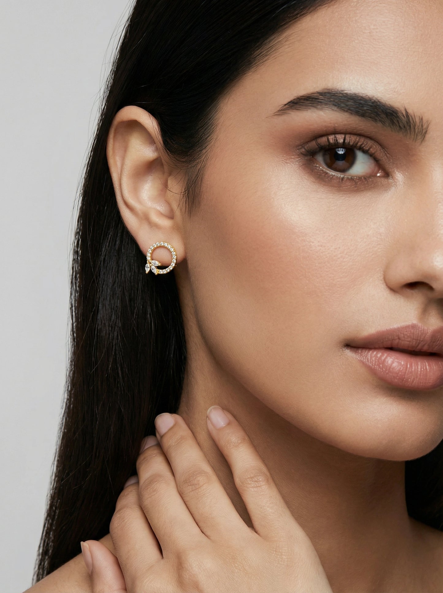 close-up of a woman wearing a 18k gold plated earring with a gray background