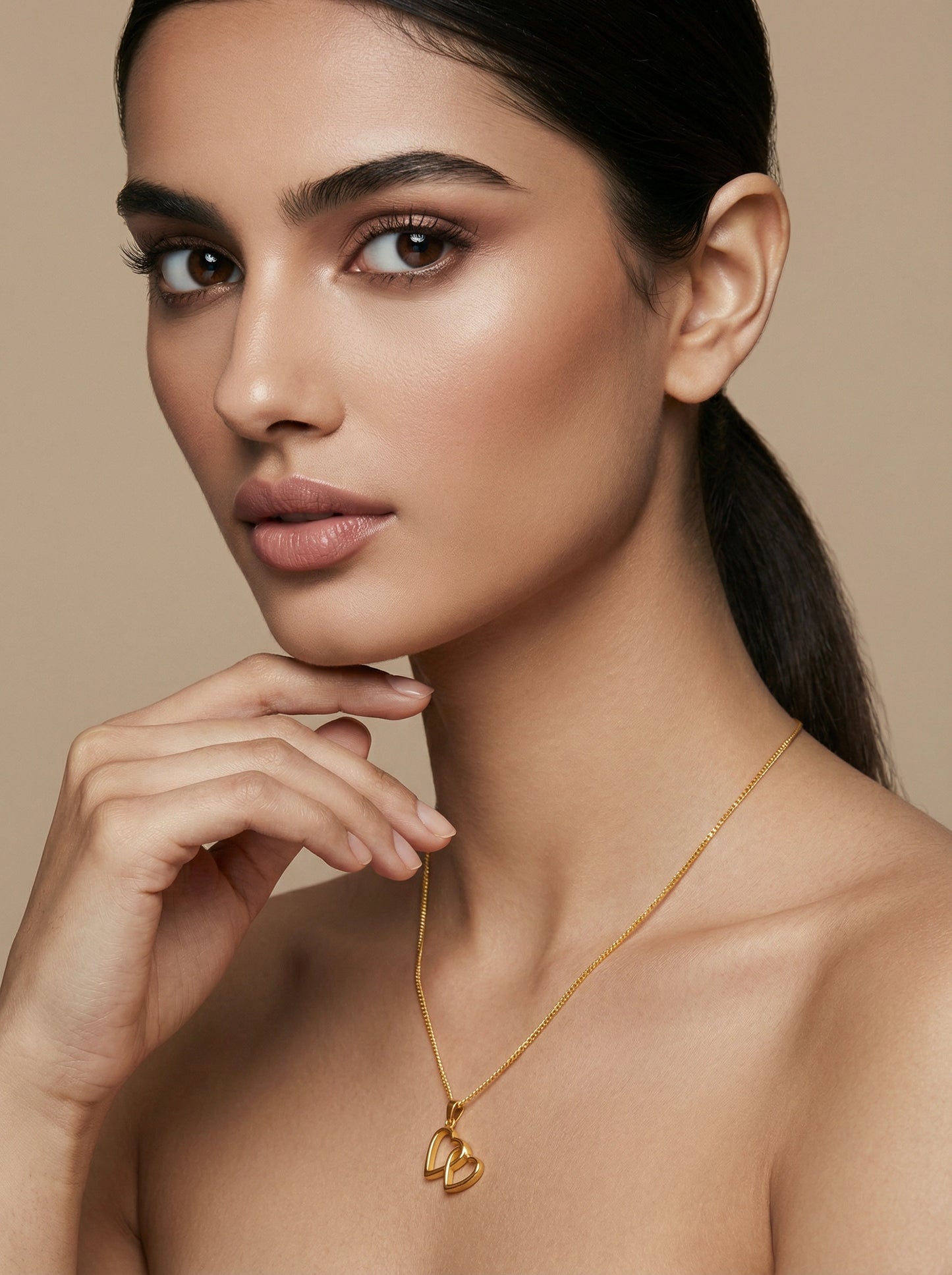 woman wearing a 18k gold plated necklace against a beige background