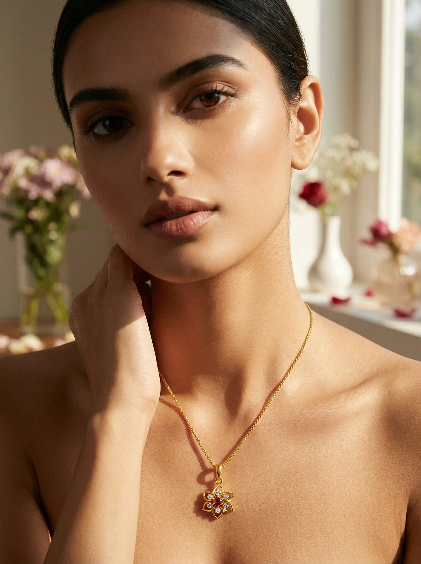 woman wearing a 18k gold plated necklace with a floral pendant in a softly lit room.