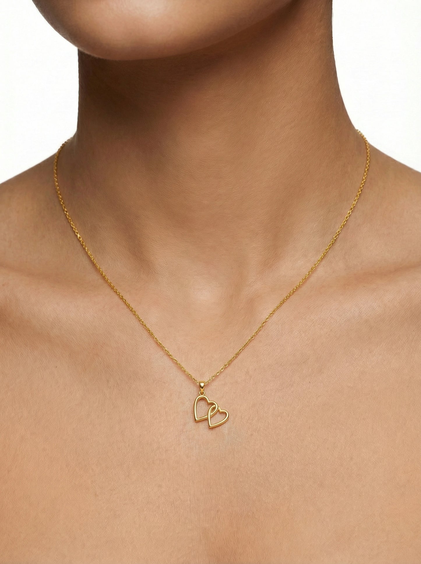 18k gold plated necklace with heart pendants on a person's neck against a neutral background