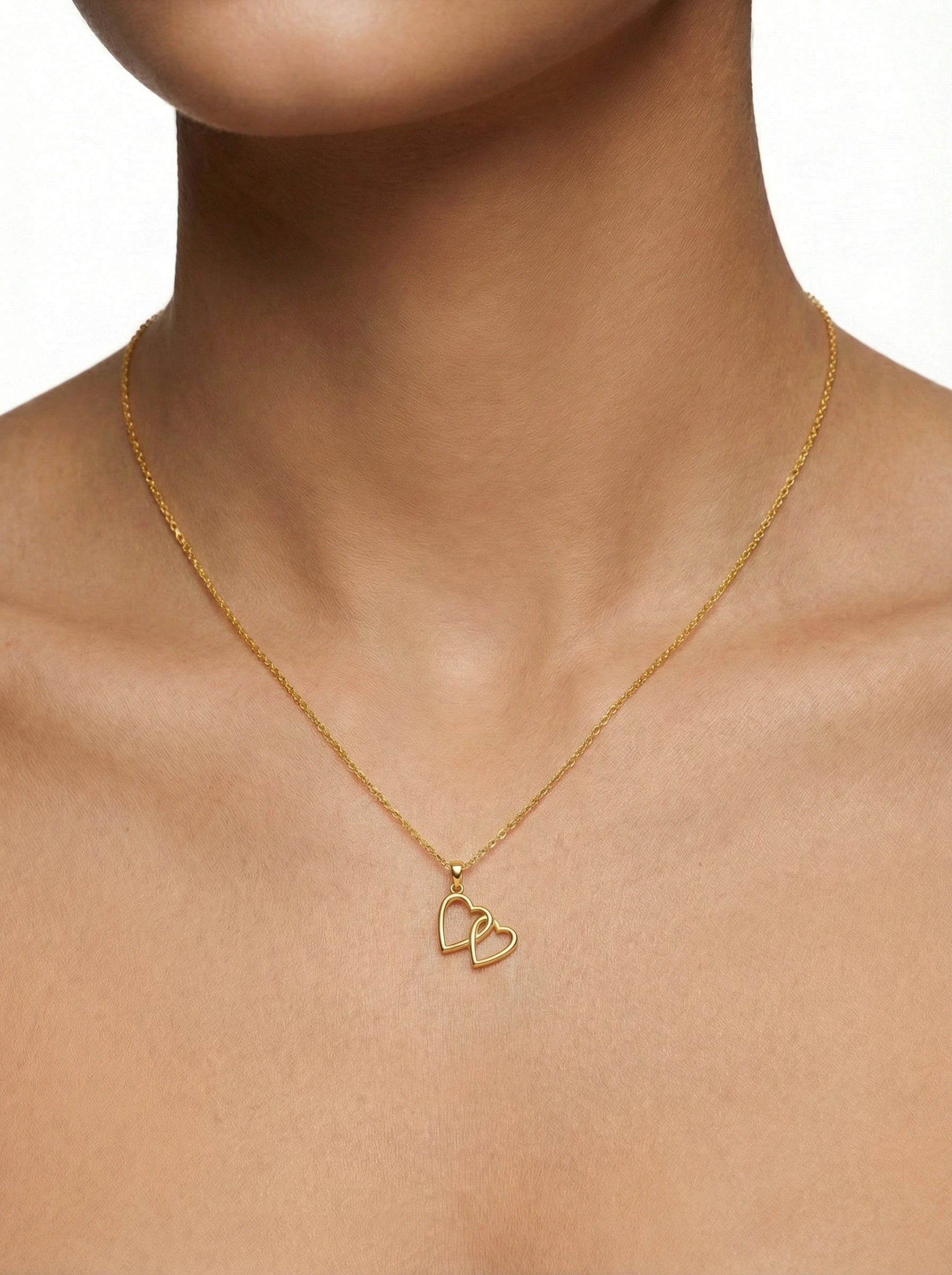 18k Gold plated necklace with heart pendants on a person's neck against a neutral background