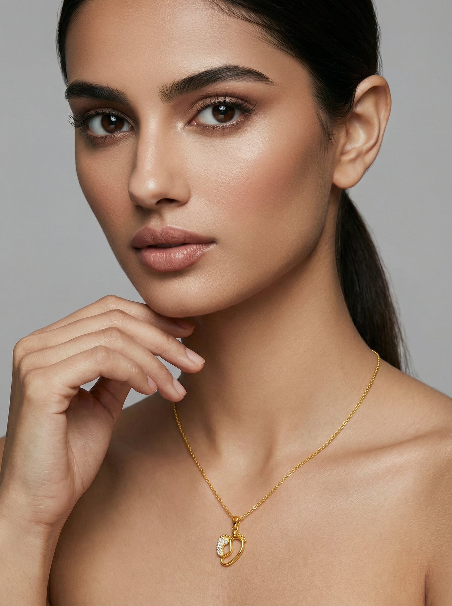 woman wearing a 18k gold plated necklace with a heart pendant against a neutral background