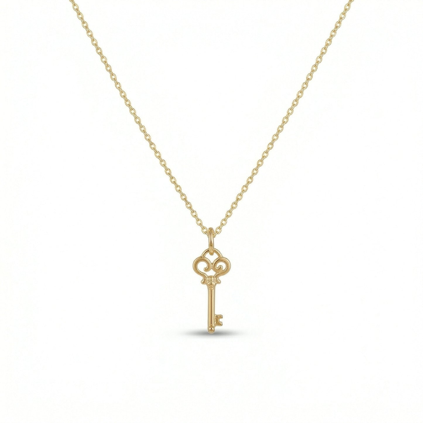 18k gold  plated  key-shaped pendant on a chain against a white background