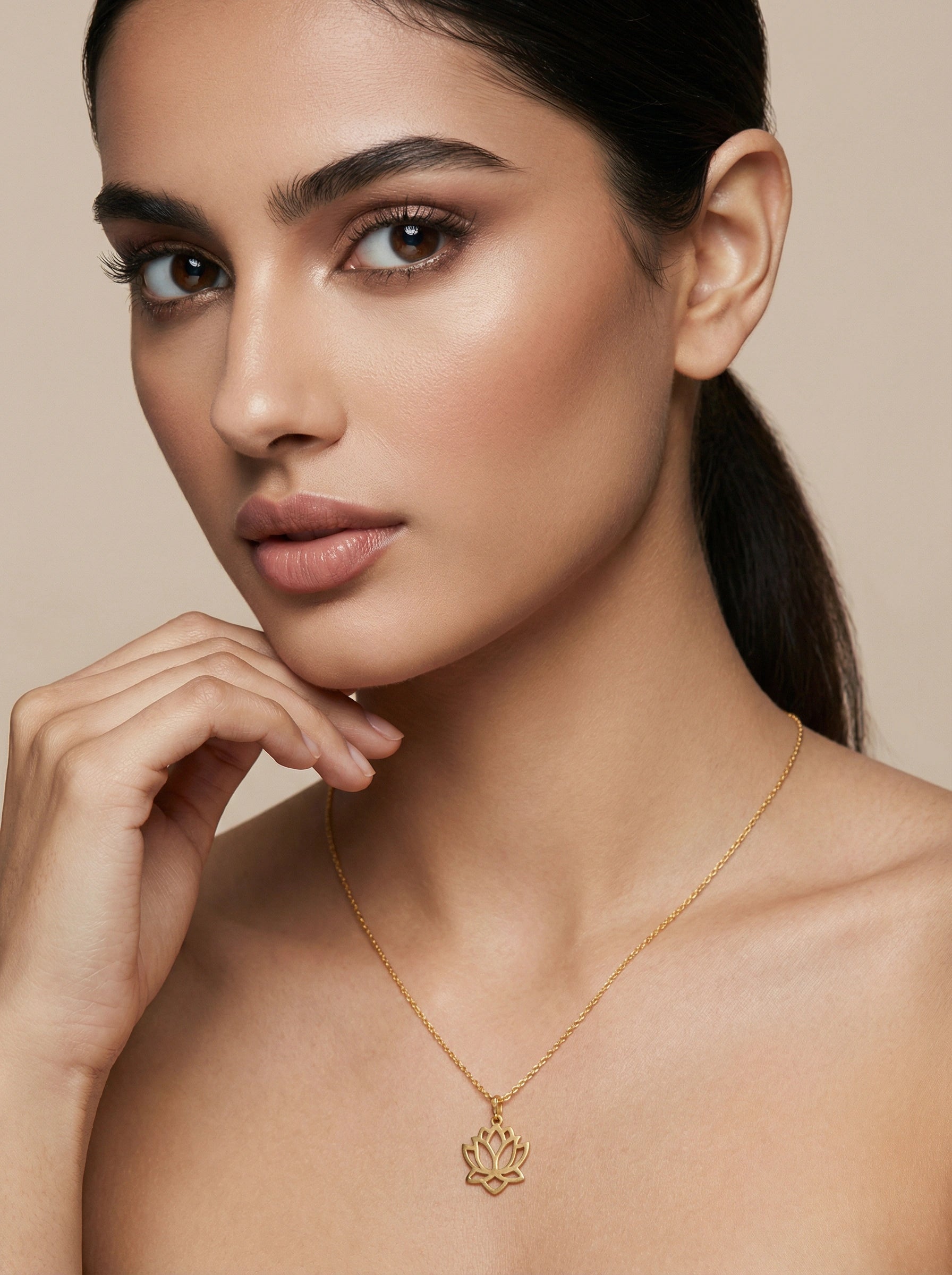 Woman wearing a 18k gold plated necklace with a lotus pendant against a beige background