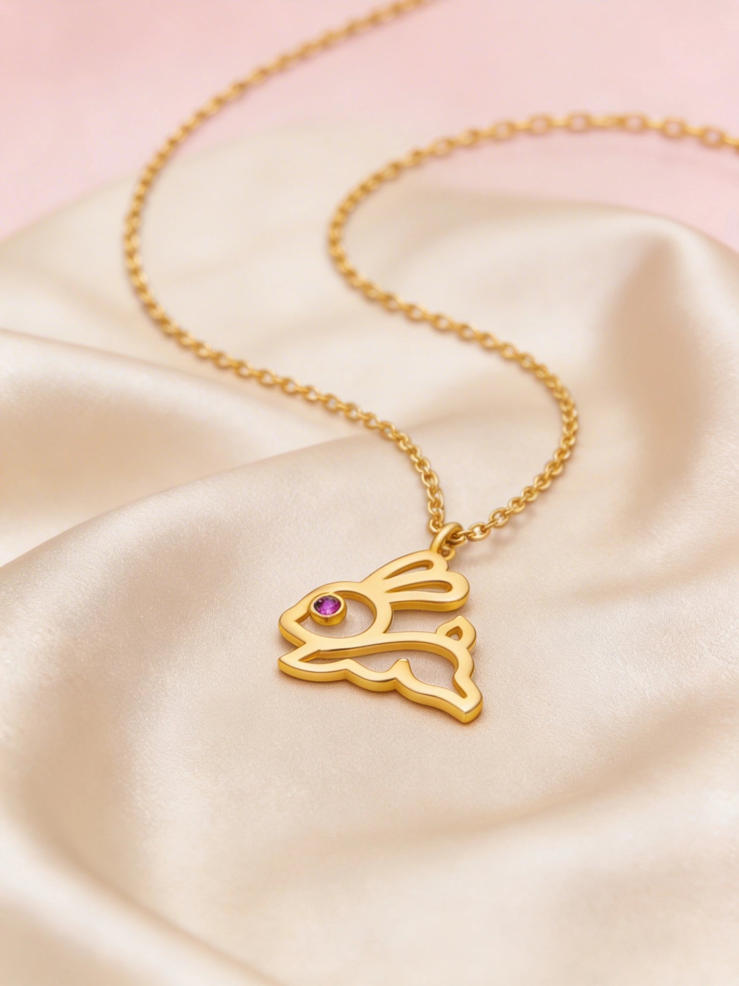 18k gold plated necklace with a rabbit pendant on a pink satin background