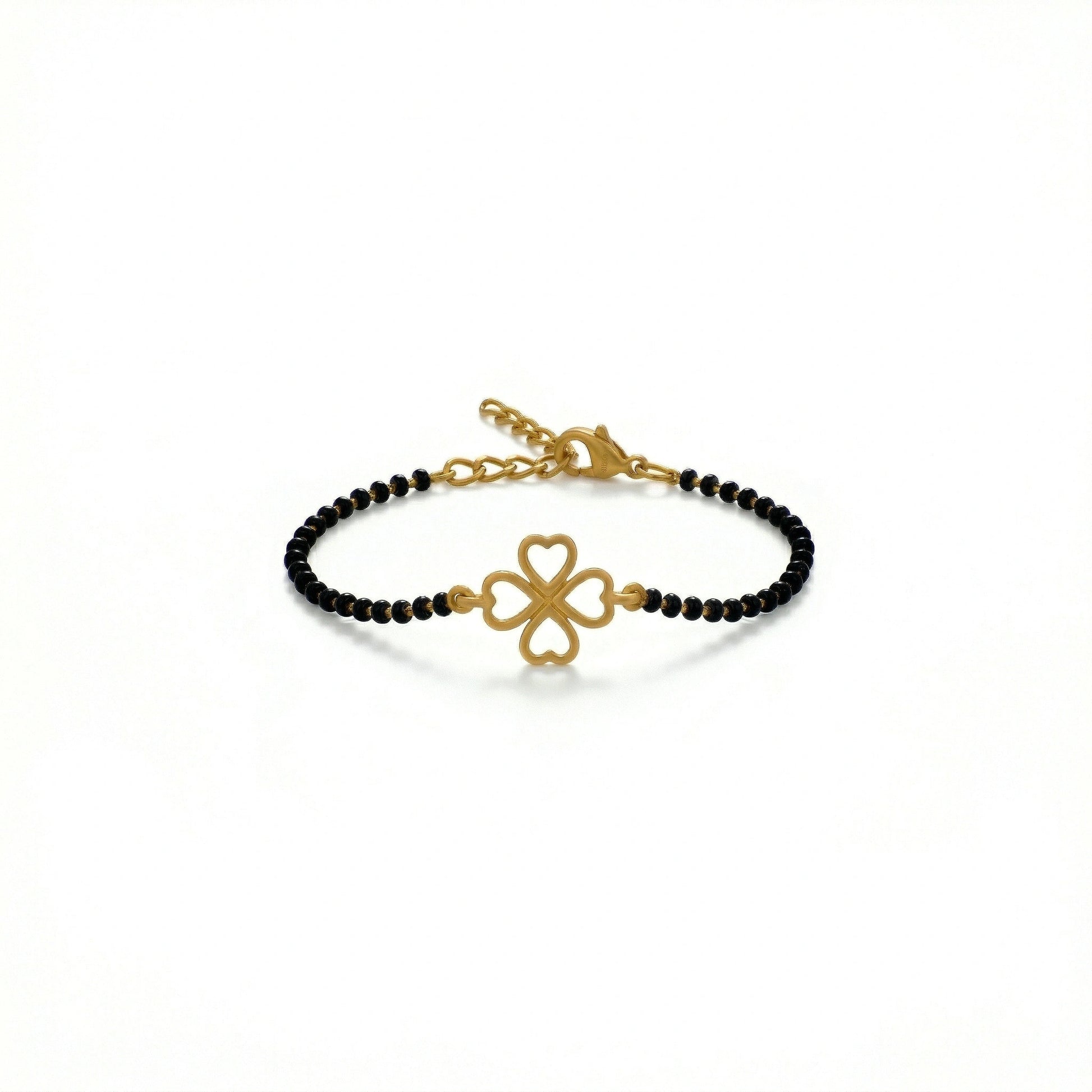 Gold bracelet with black beads and clover charm on a white background