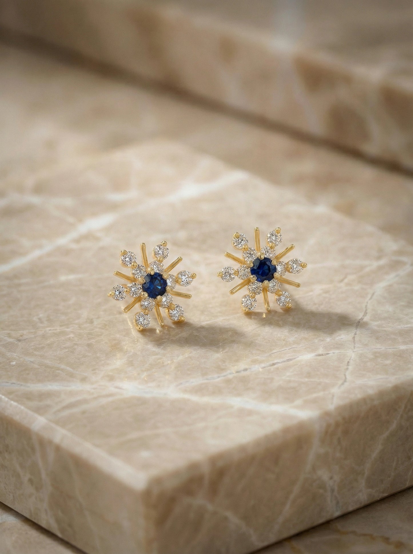 18k gold plated earrings with blue gemstones on a marble surface