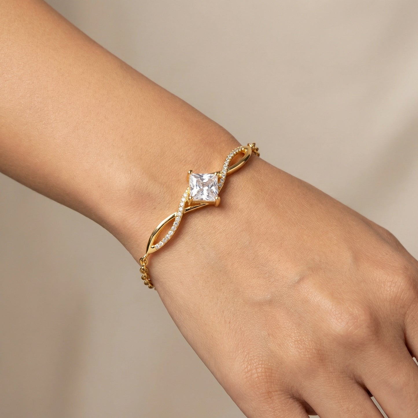 18k gold plated bracelet with a diamond on a wrist against a neutral background