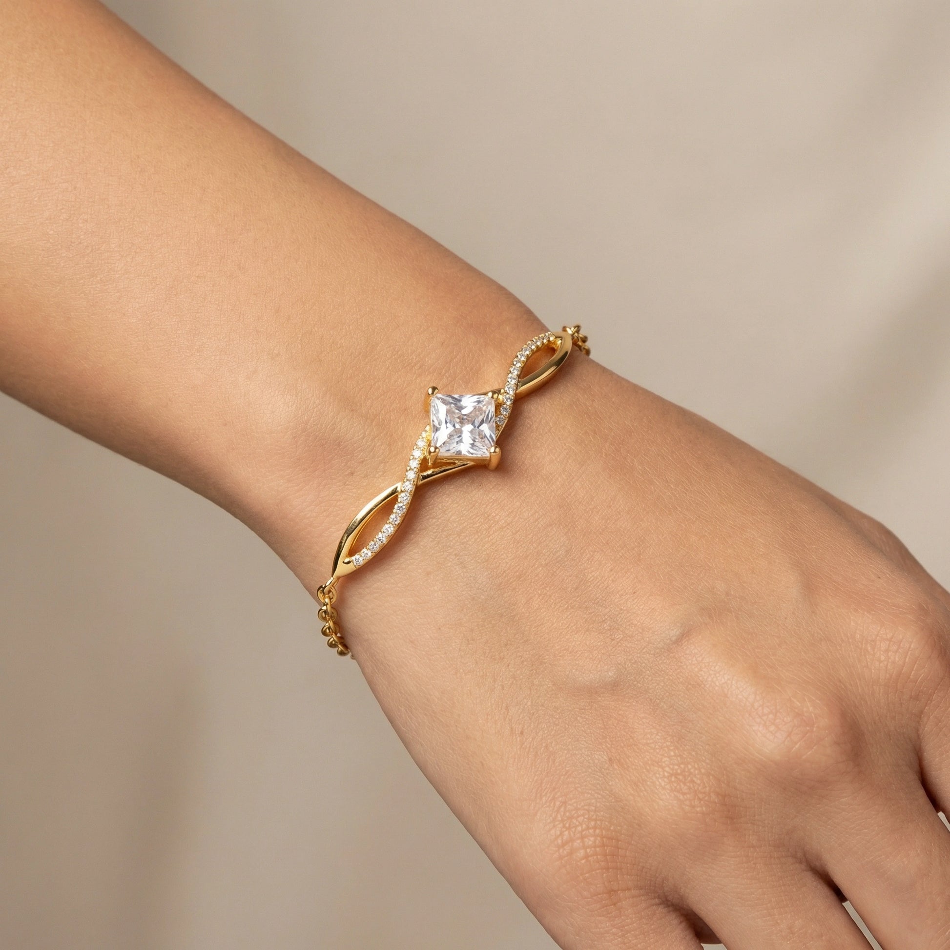 18k Gold plated bracelet with a diamond on a wrist against a neutral background
