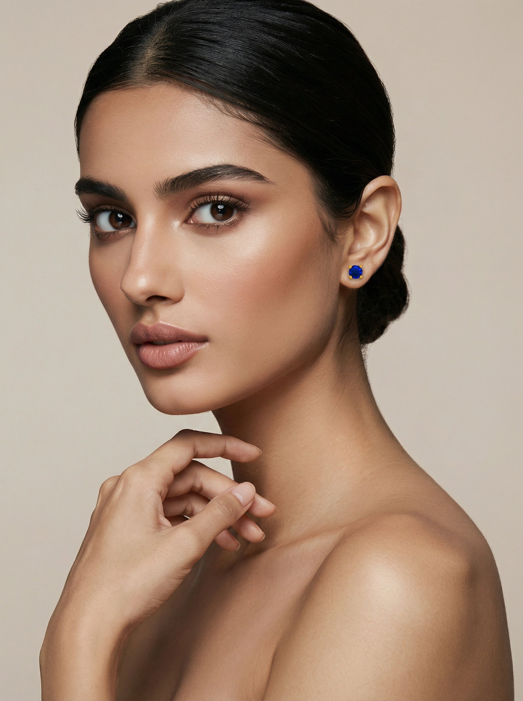 Woman wearing a blue earring 18k gold plated against a beige background