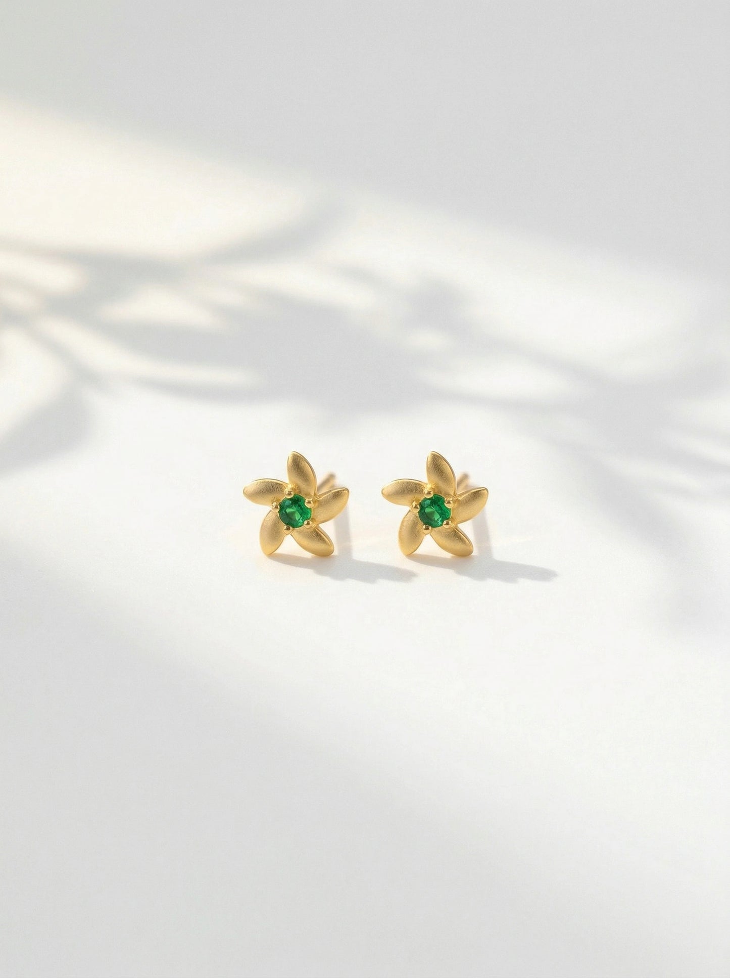 18k gold plated  earrings with green gemstones on a light background