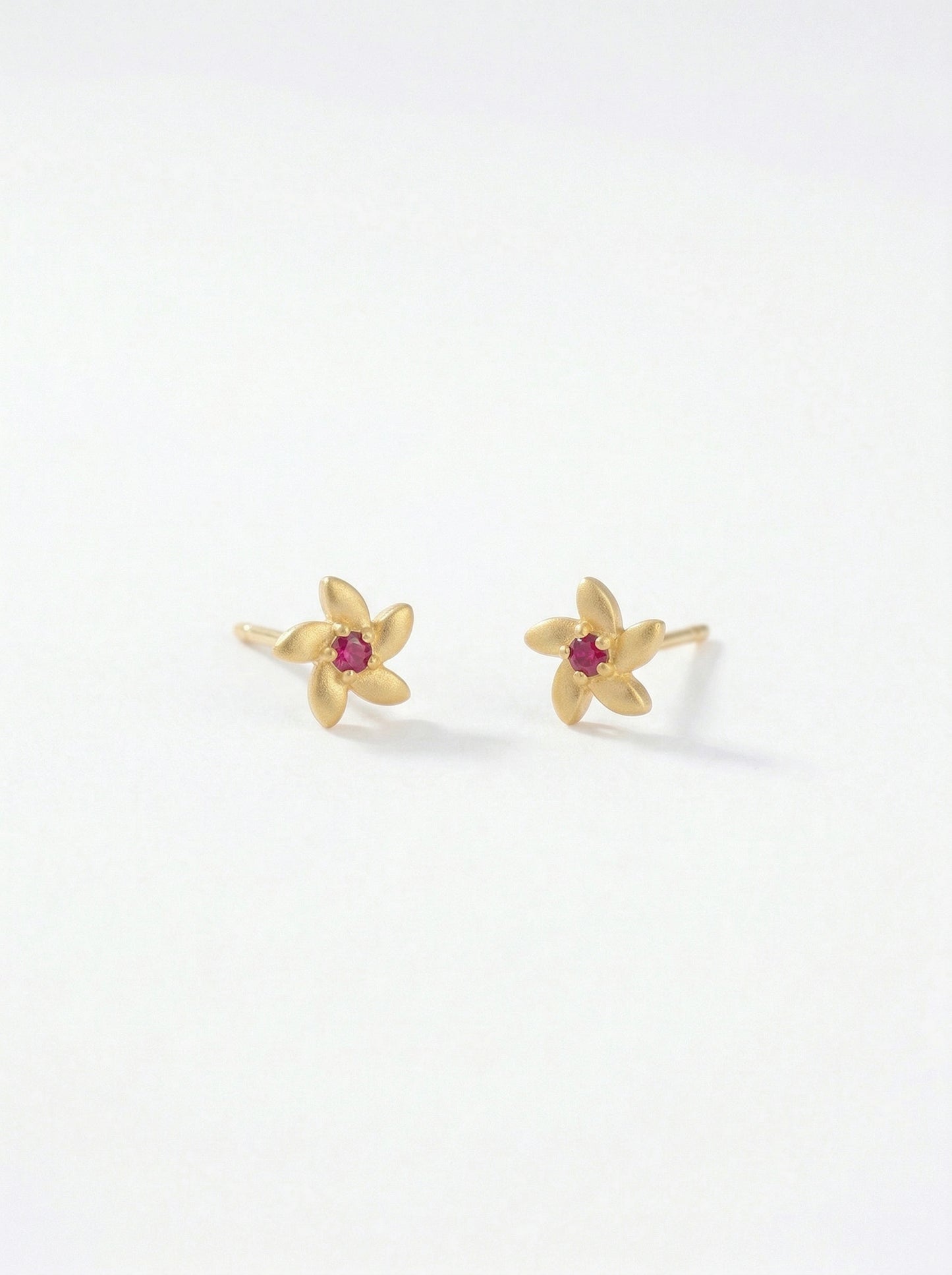 18k gold plated flower-shaped earrings with red gemstones on a white background