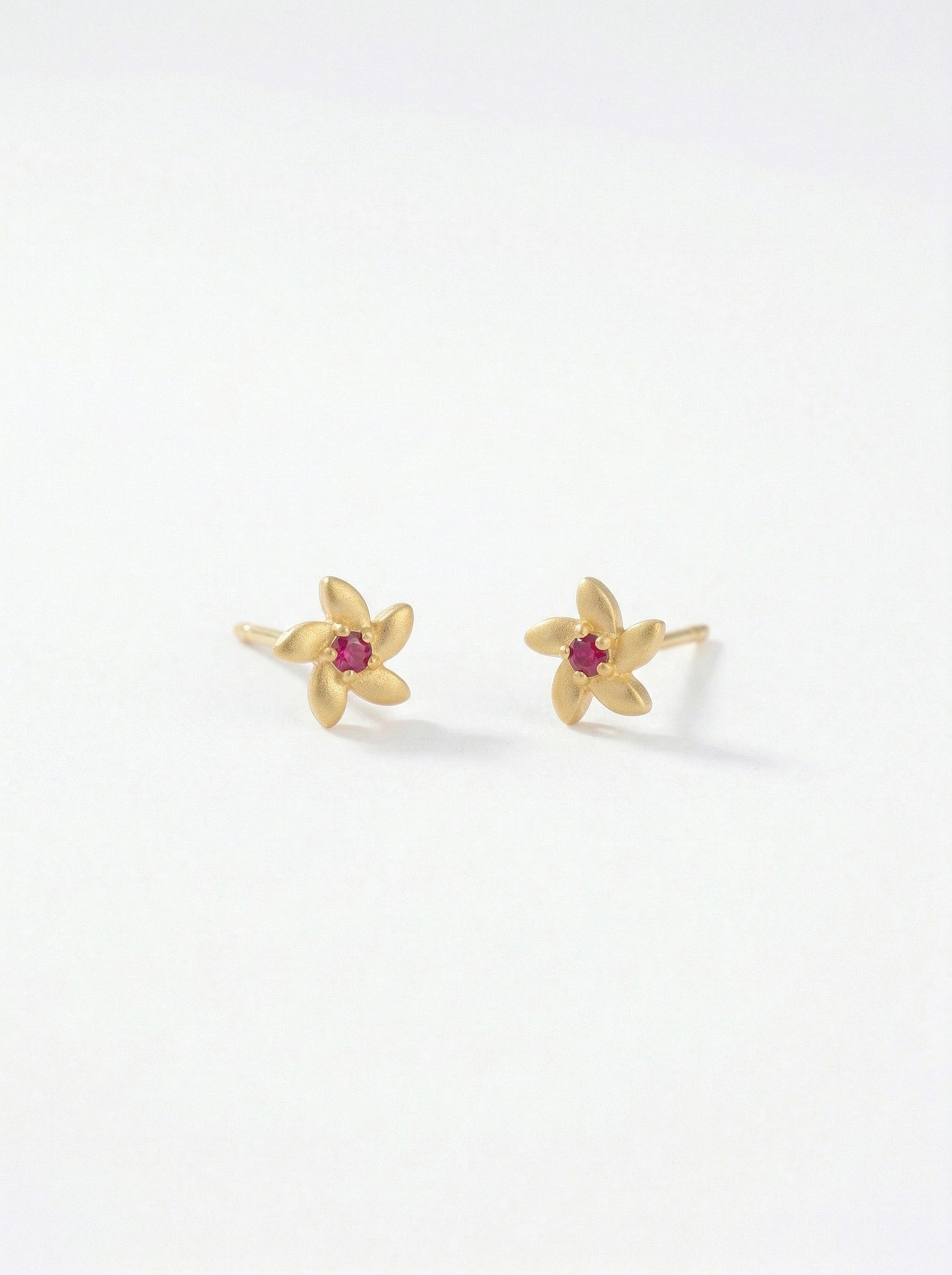 18k Gold plated flower-shaped earrings with red gemstones on a white background