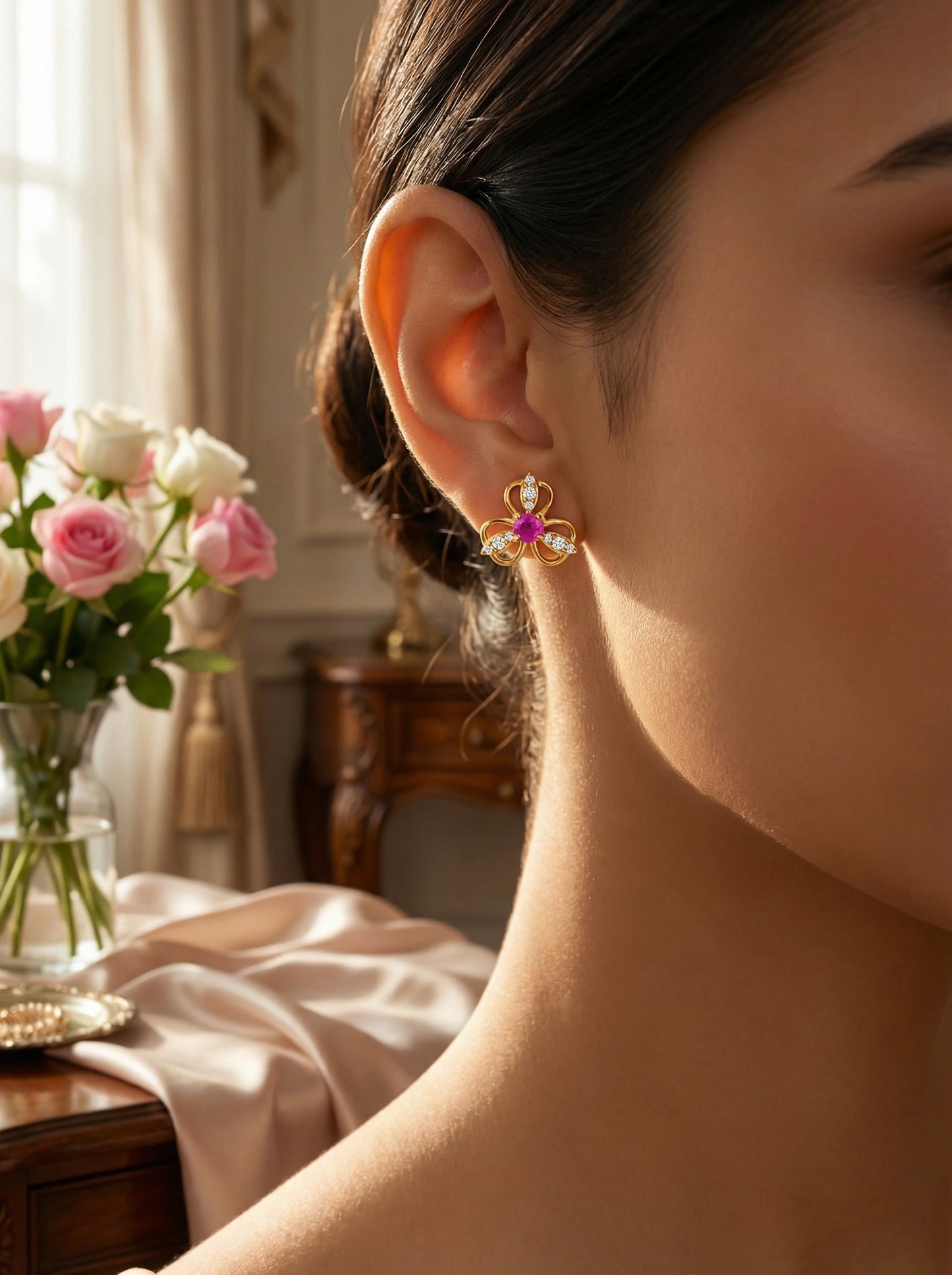 close-up of a person wearing a 18k gold plated decorative earring with a blurred background of flowers and furniture.