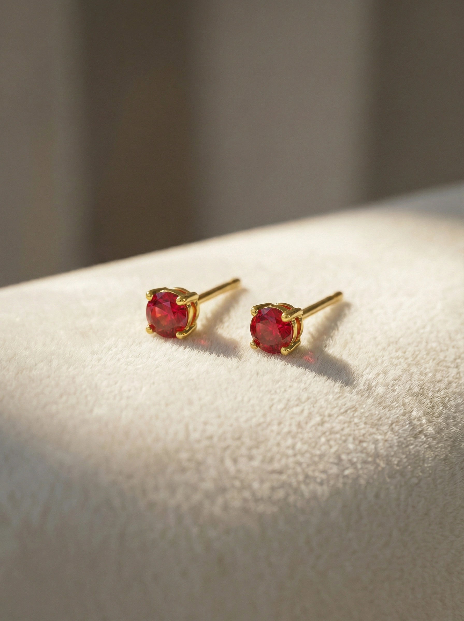 18k Gold plated earrings with red gemstones on a light surface
