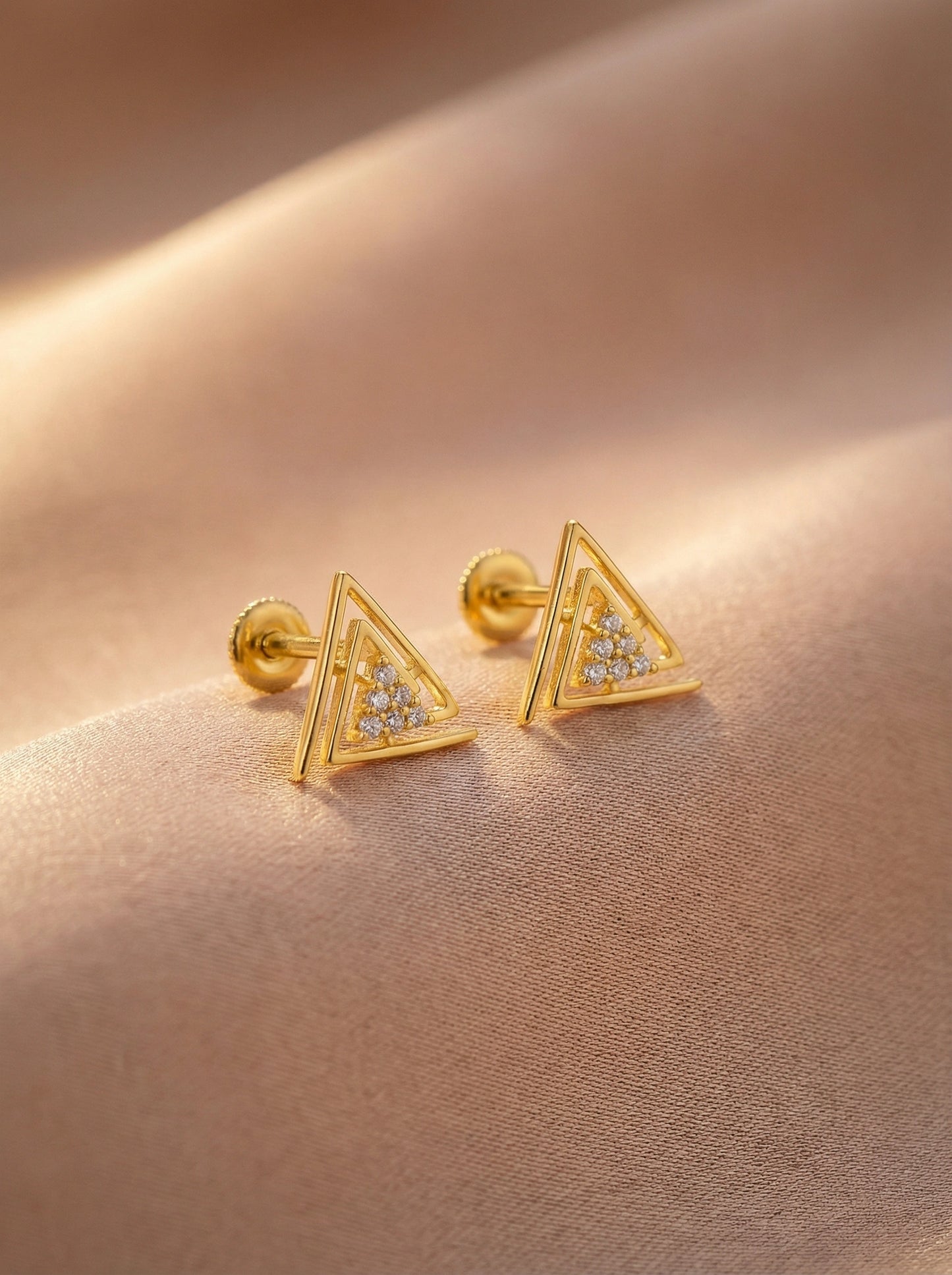 18k gold plated  triangle-shaped earrings with embedded stones on a beige fabric background