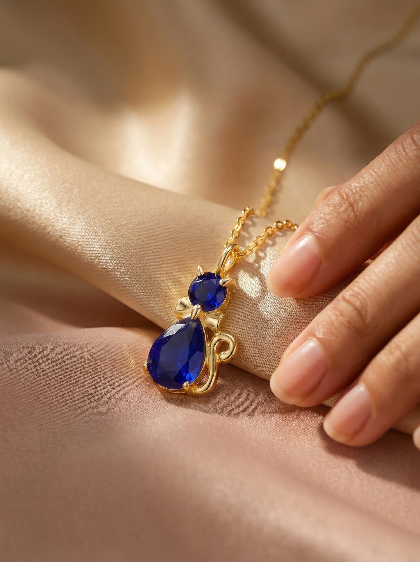 18k gold plated necklace with blue teardrop-shaped gemstones on a soft beige background