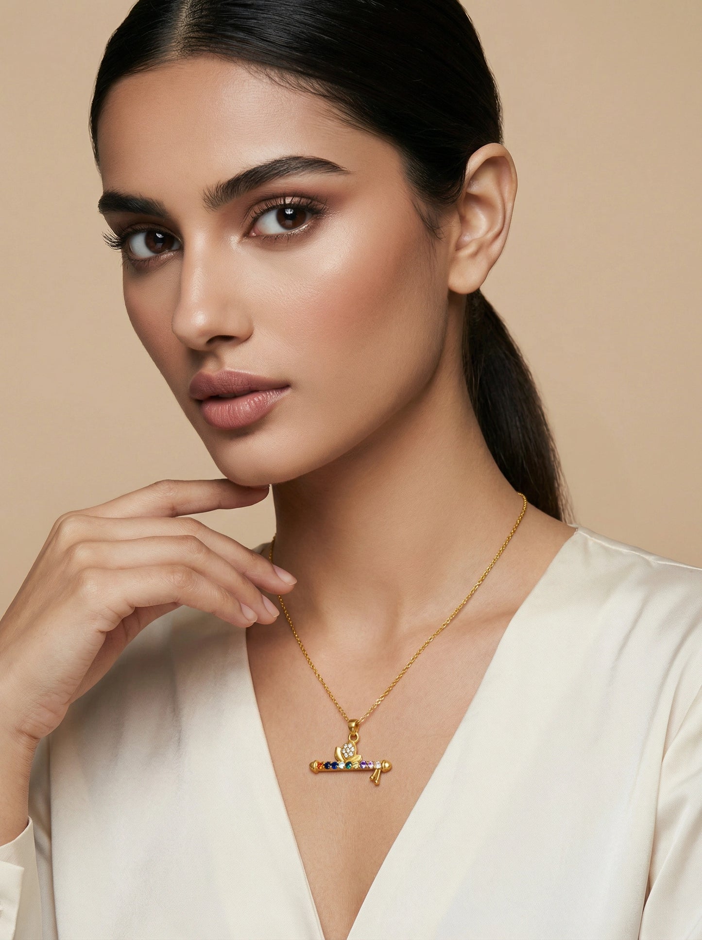 woman wearing a 18k  gold plated necklace with a colorful pendant against a beige background