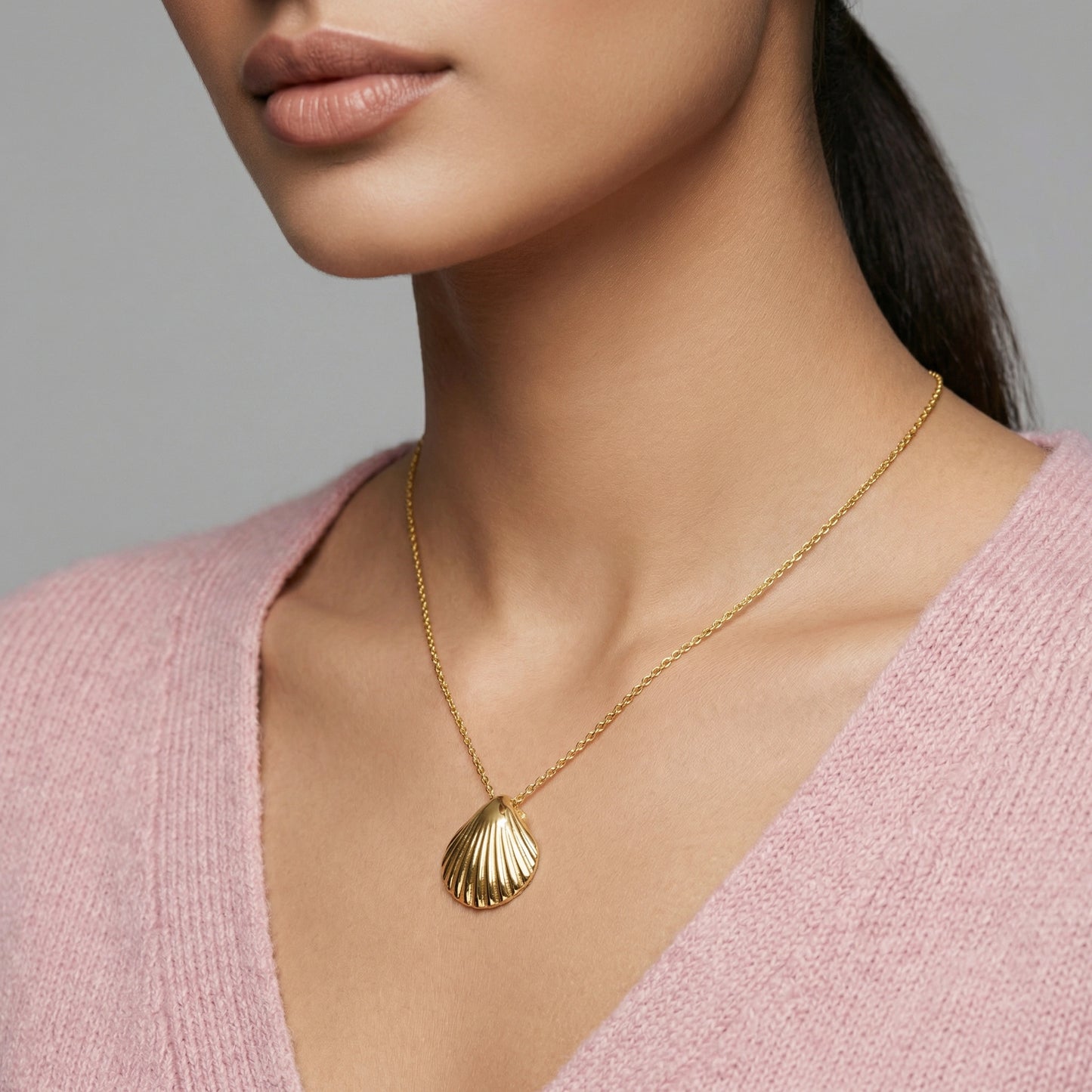 18k gold plated necklace with a shell pendant worn by a person in a pink sweater.