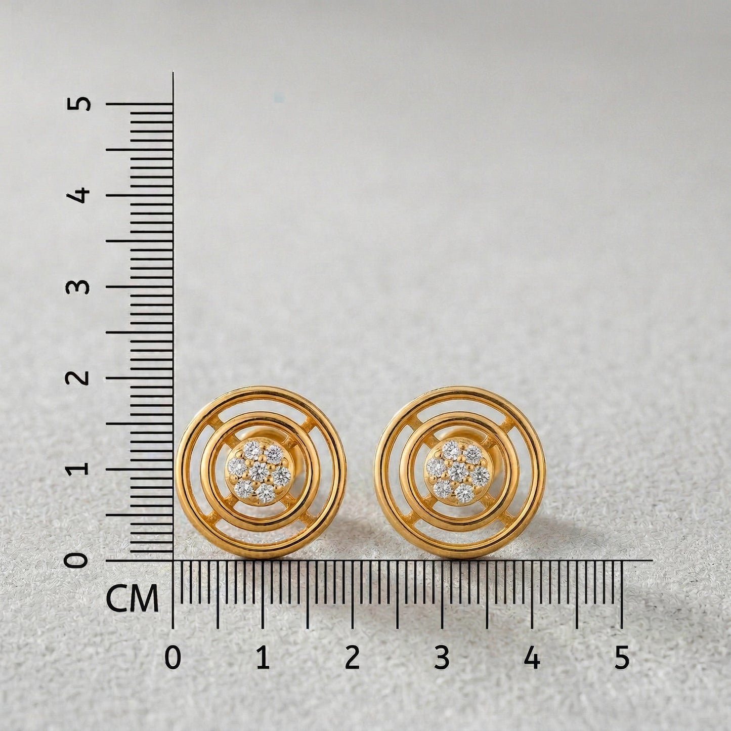 18k gold plated earrings with diamond accents next to a ruler on a light gray background