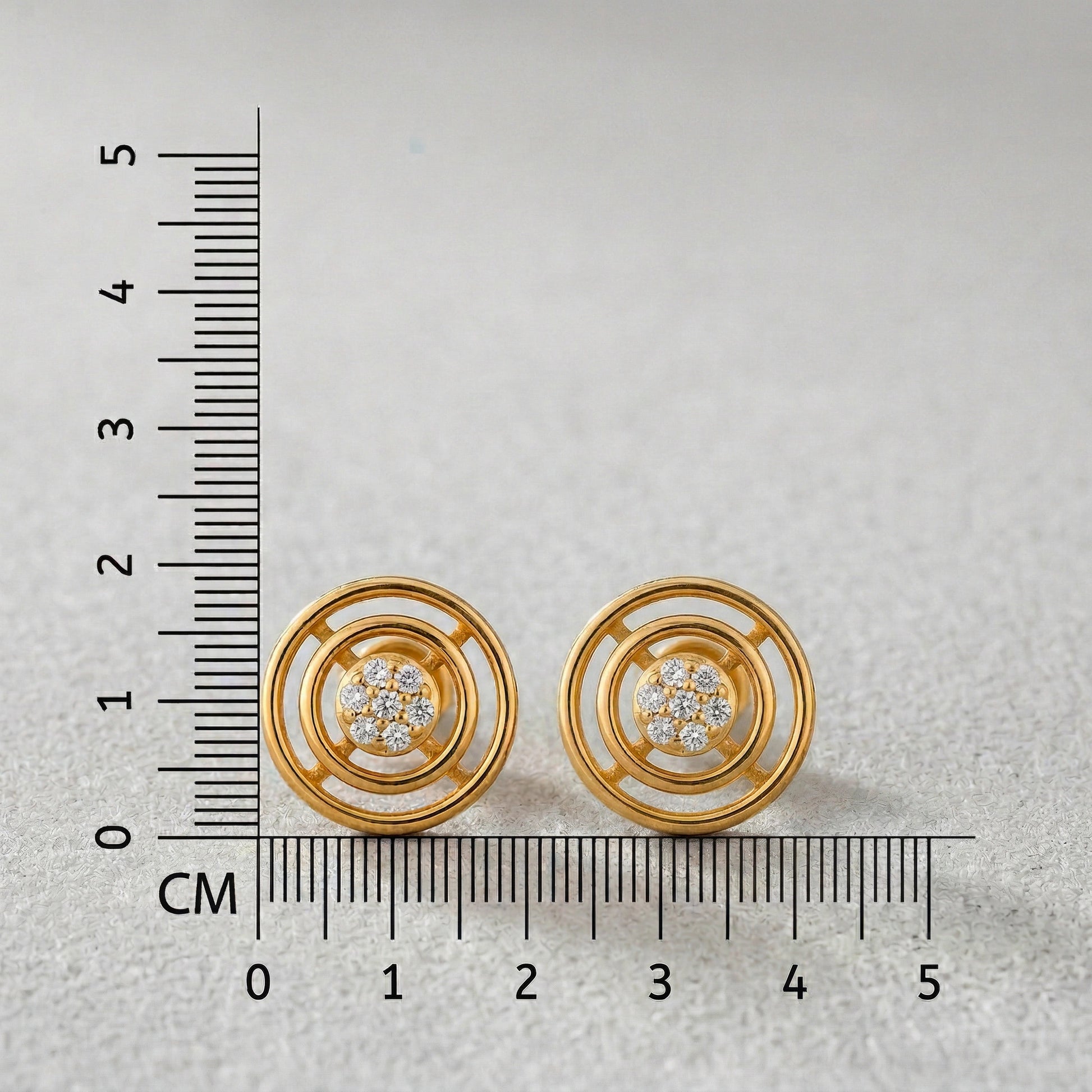 18k Gold plated earrings with diamond accents next to a ruler on a light gray background