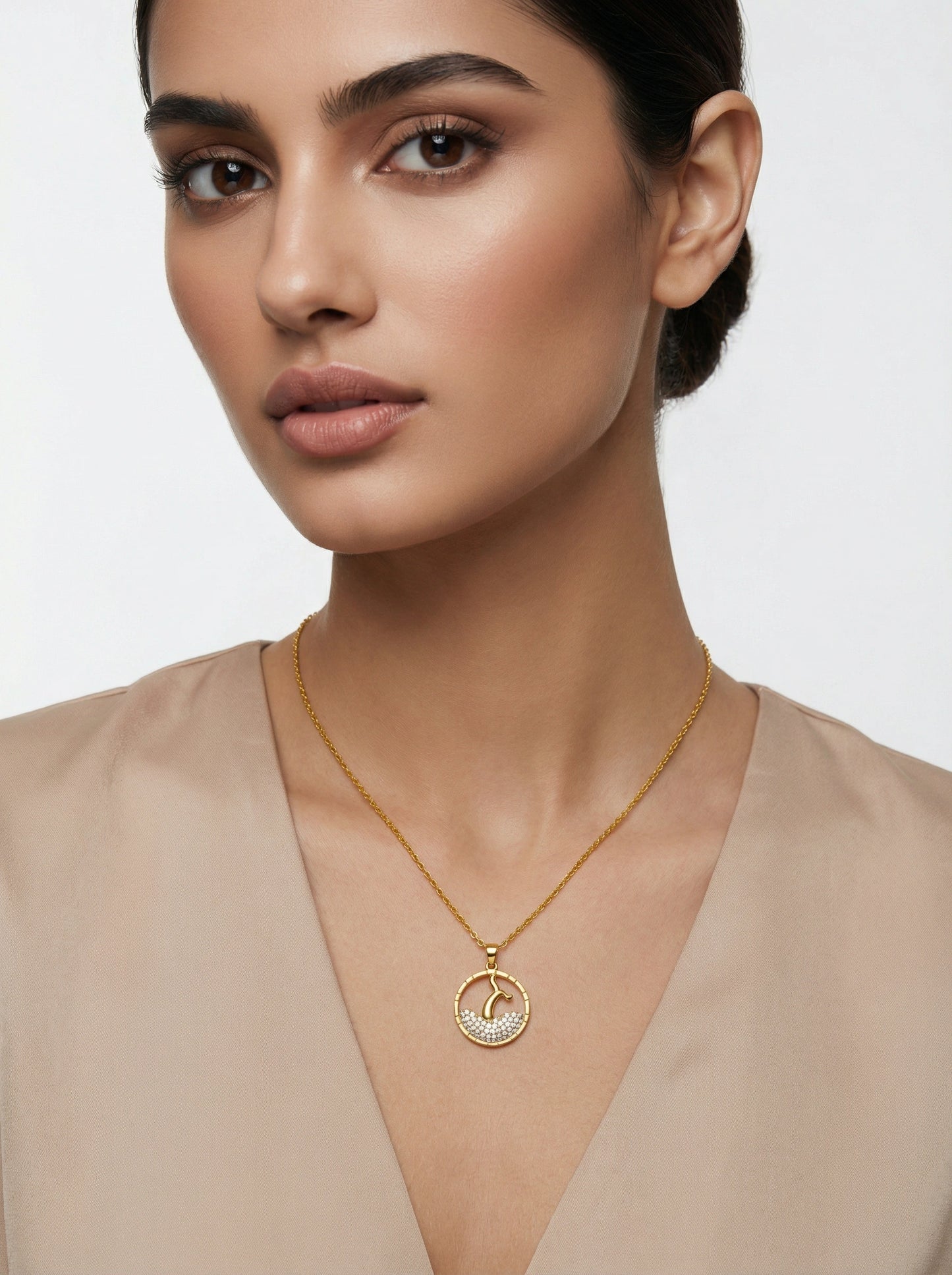 woman wearing a 18k gold plated necklace with a circular pendant on a plain background