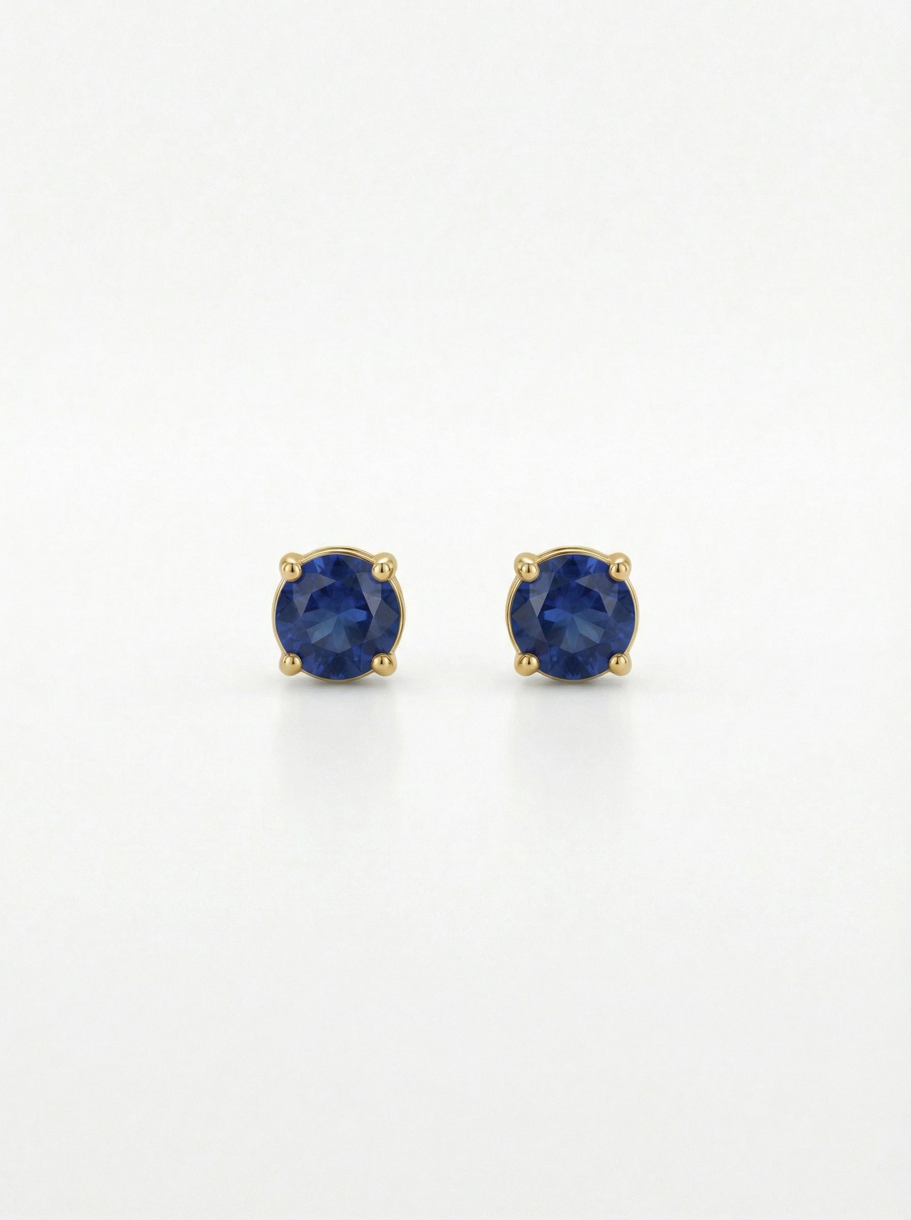 Pair of 18k gold plated earrings with blue gemstones on a white background