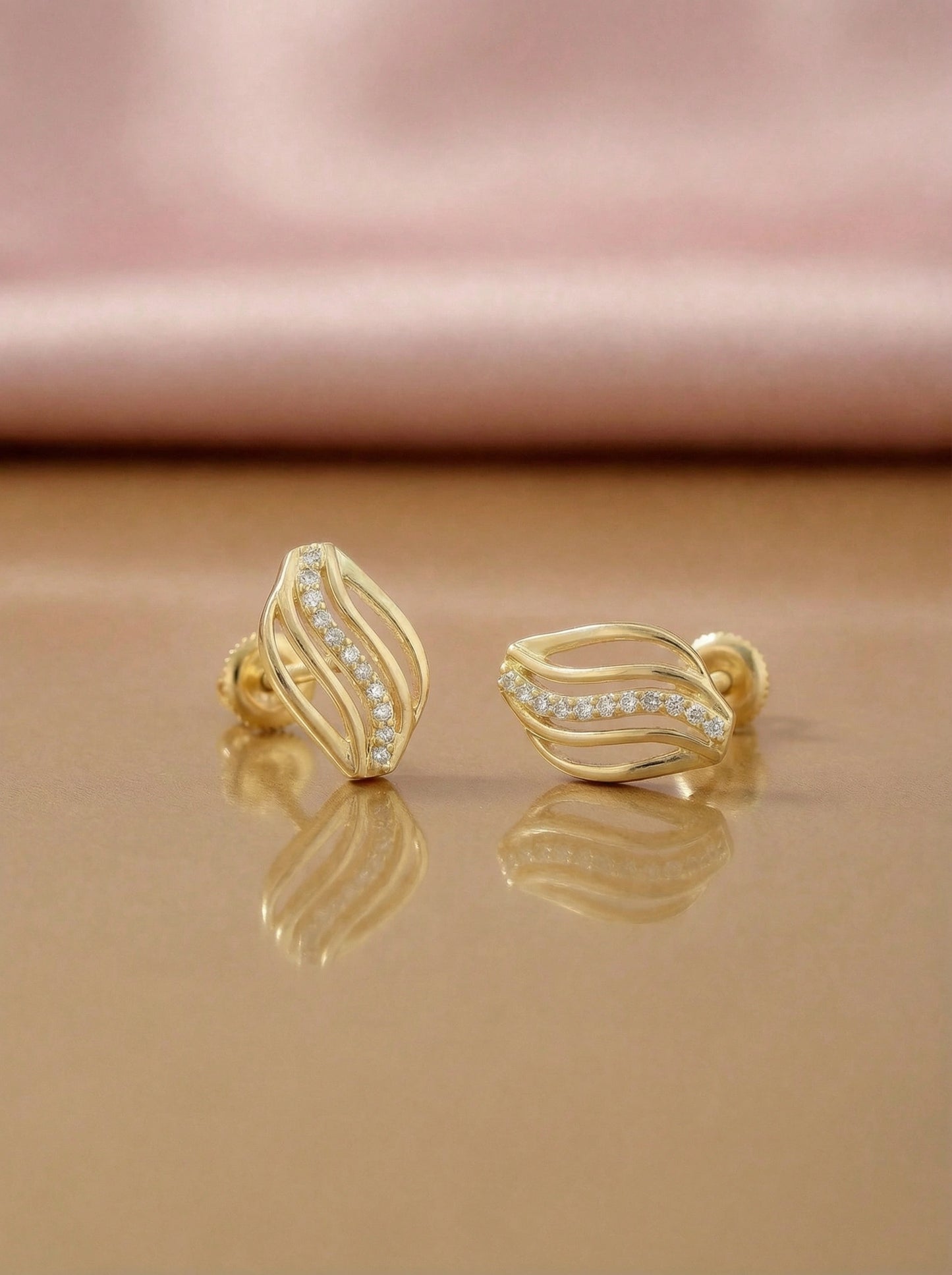 18k gold plated earrings with diamond accents on a reflective surface