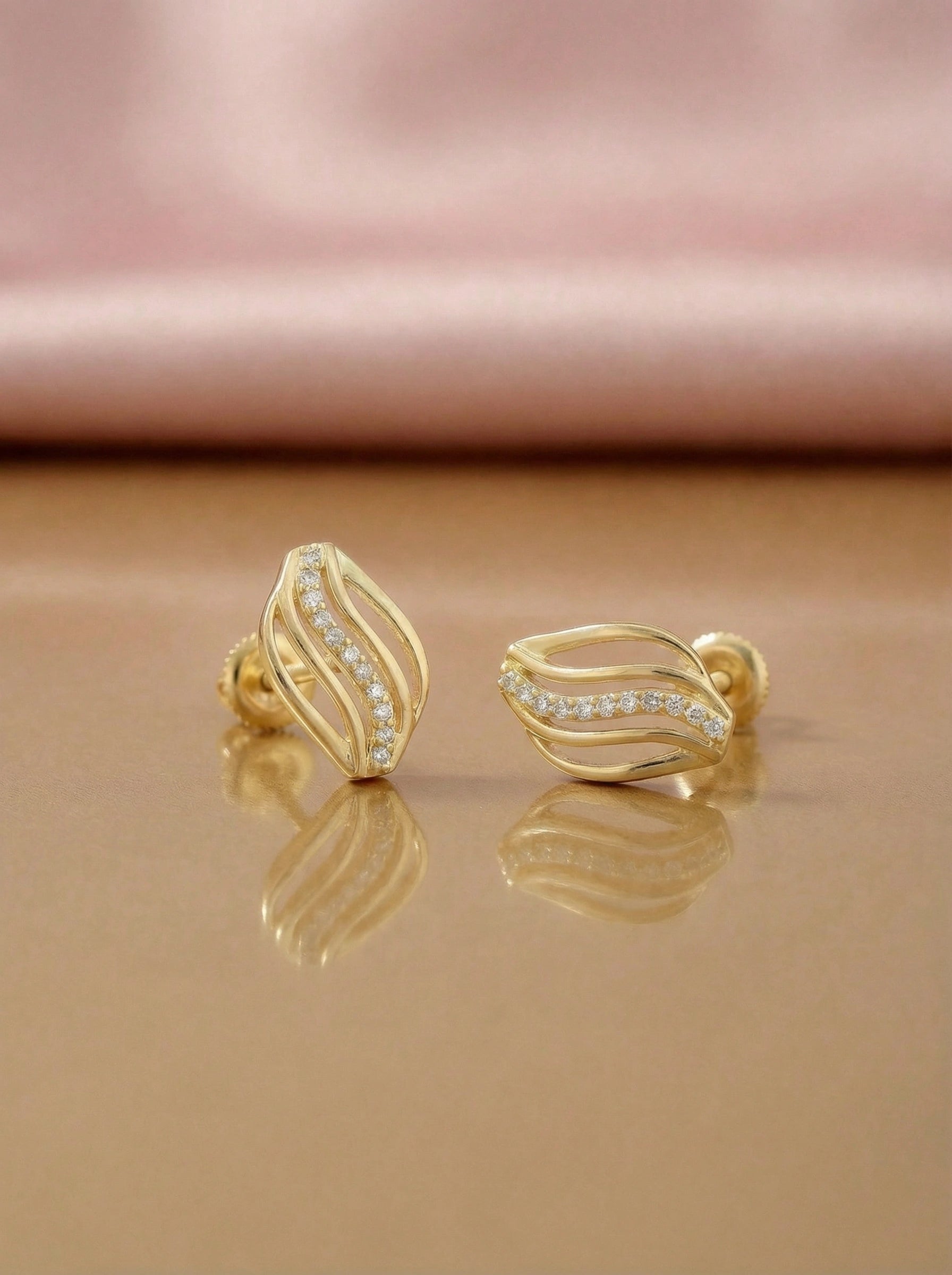 18k Gold plated earrings with diamond accents on a reflective surface