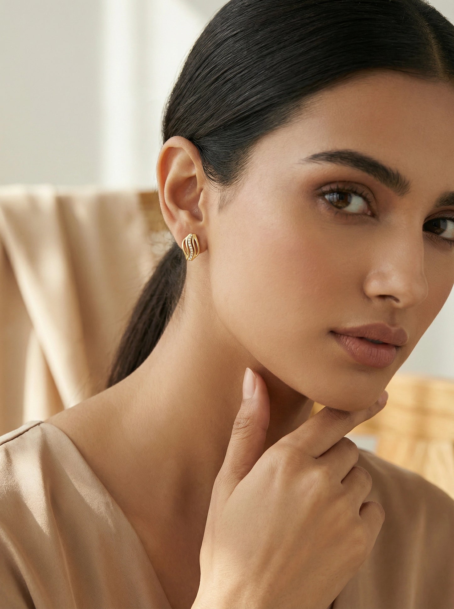woman wearing 18k  gold plated earrings with a neutral background