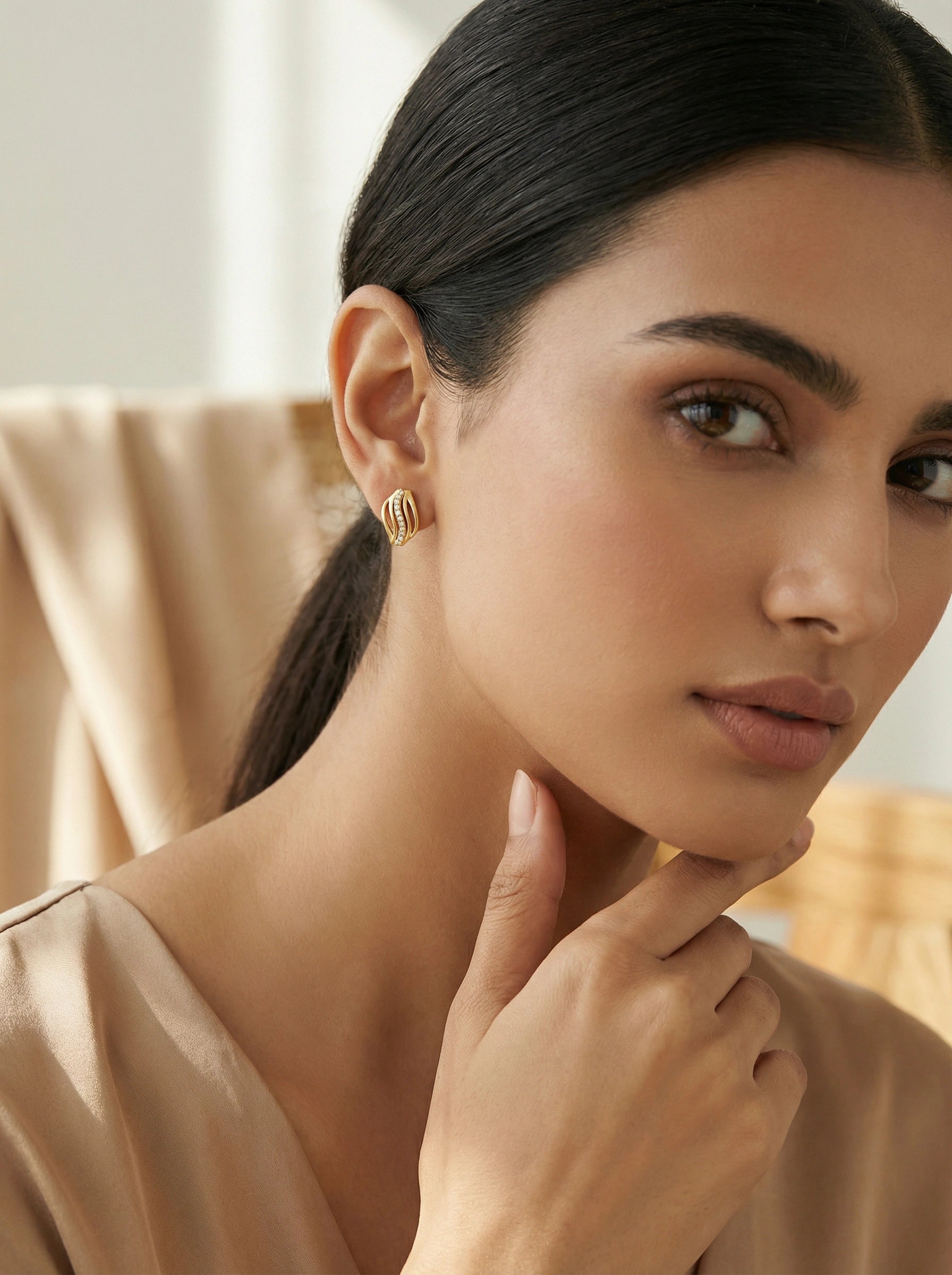 Woman wearing 18k  gold plated earrings with a neutral background