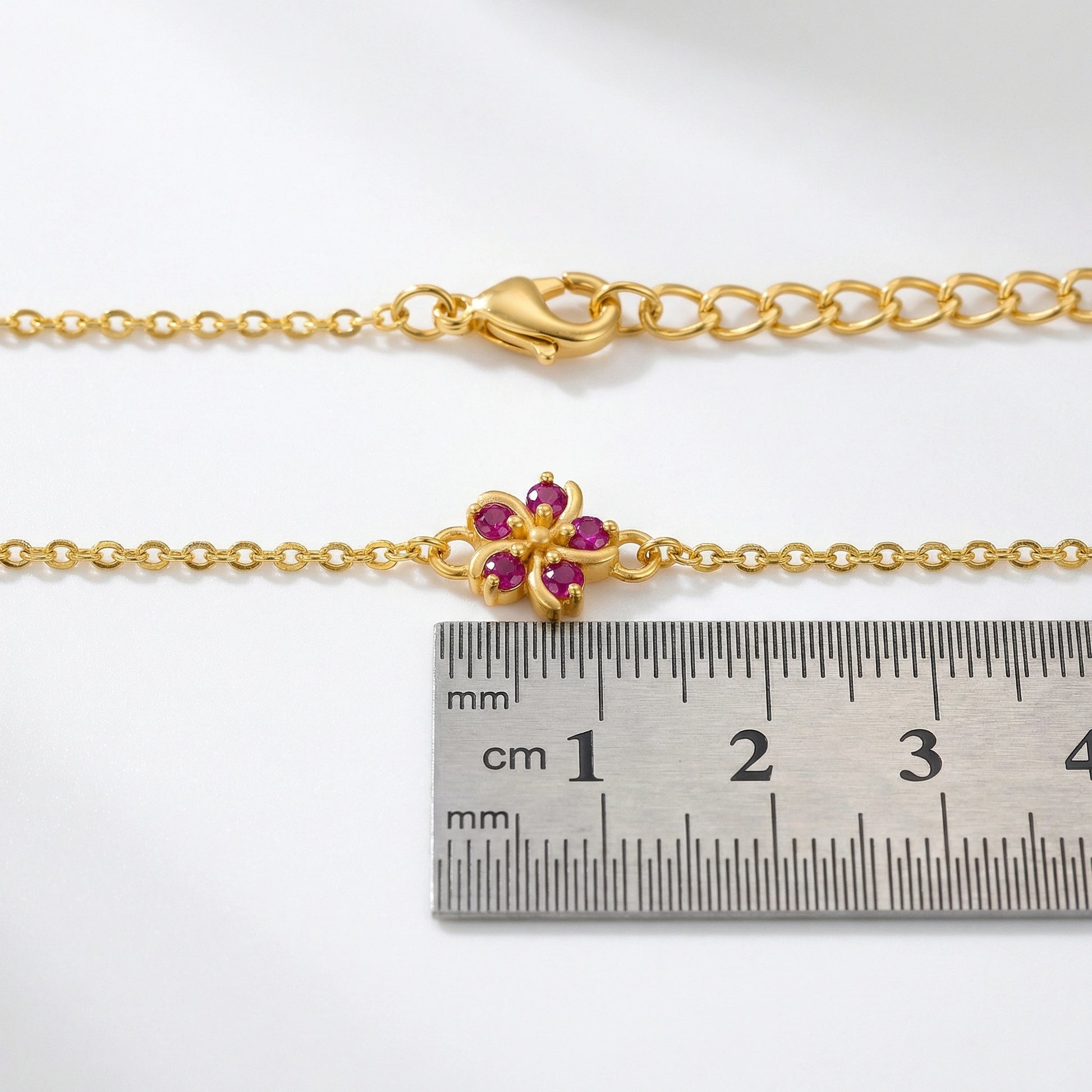 18k Gold  plated bracelet with a floral clasp next to a ruler for size reference on a white background