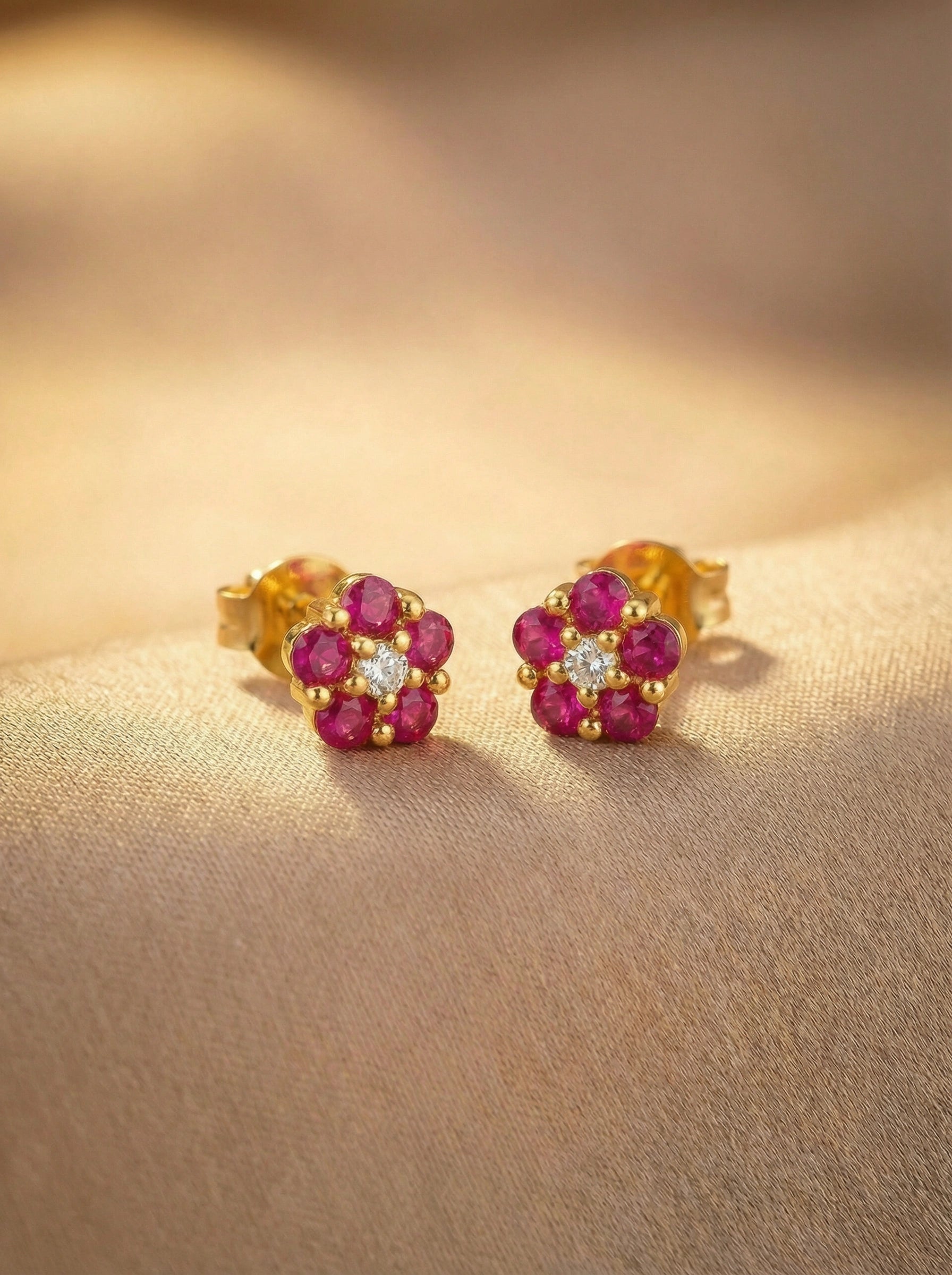 18k Gold plated earrings with red gemstones on a beige surface