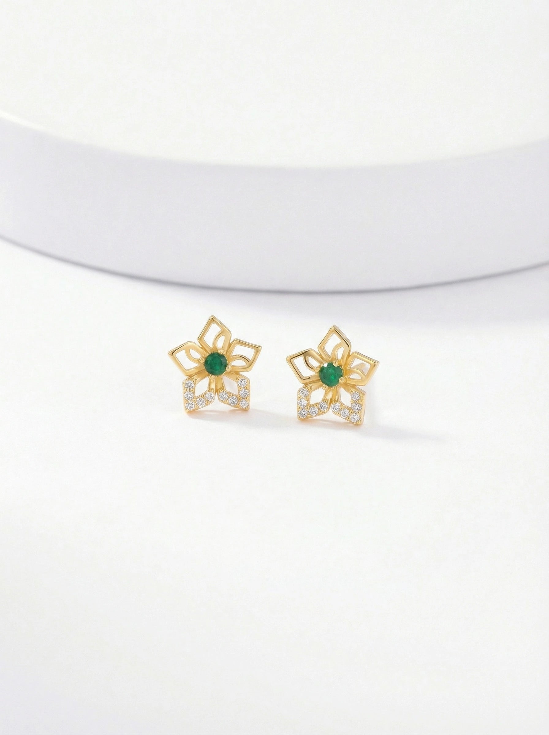 Pair of 18k gold plated earrings with green gemstones on a white background 