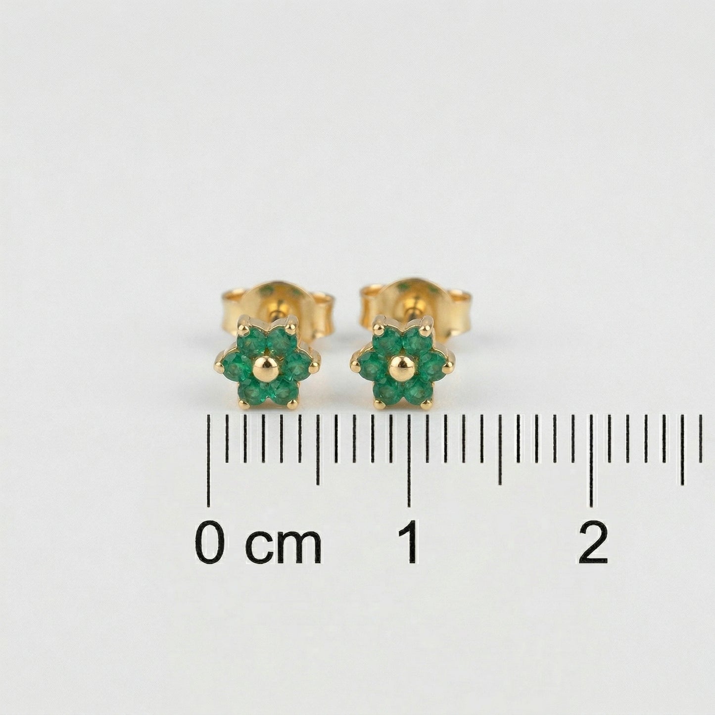 18k gold plated earrings with green gemstones on a white background with measurement scale.