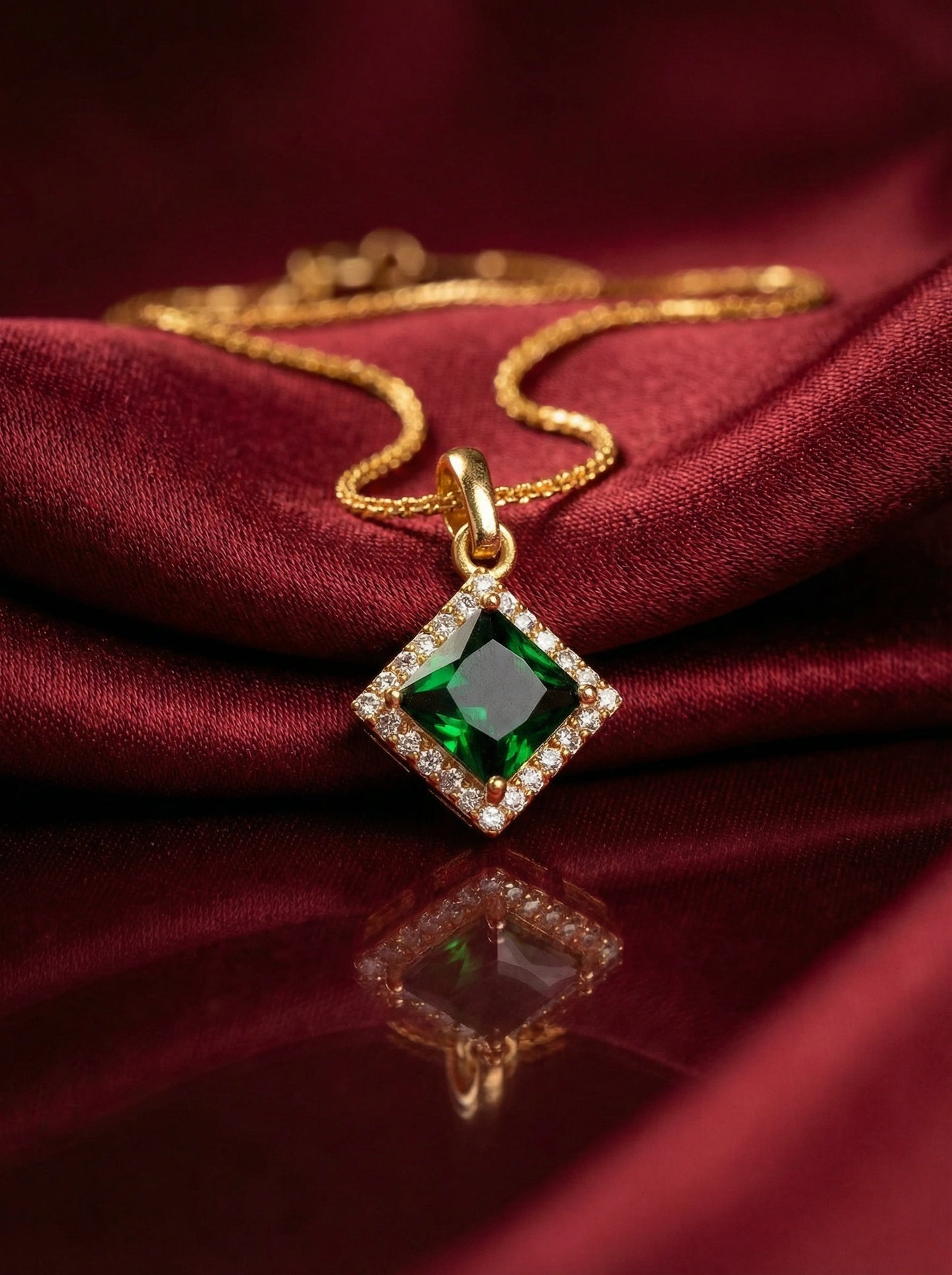 18k gold plated necklace with a green gemstone pendant on a red fabric background