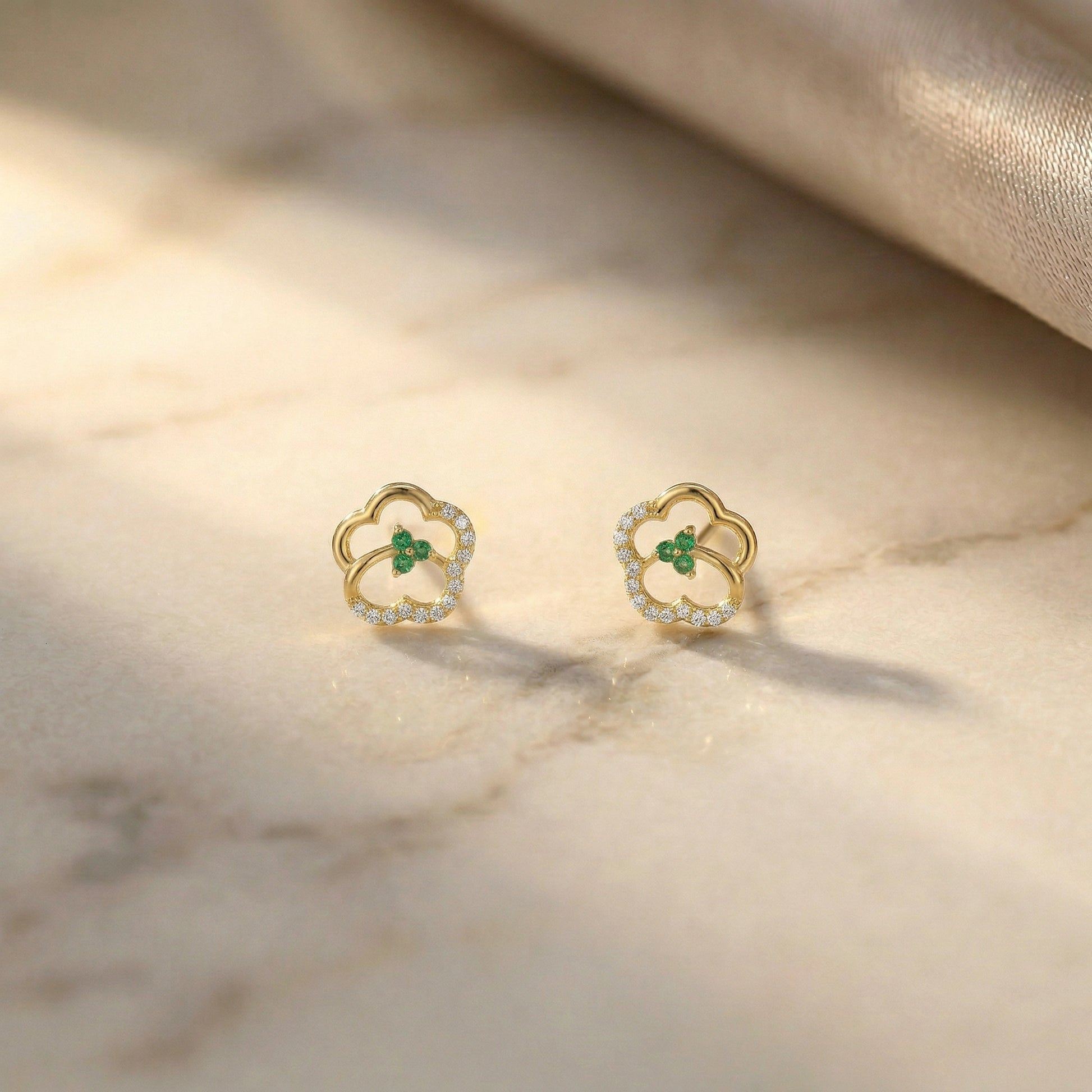 18k Gold plated earrings with green gemstones on a marble surface
