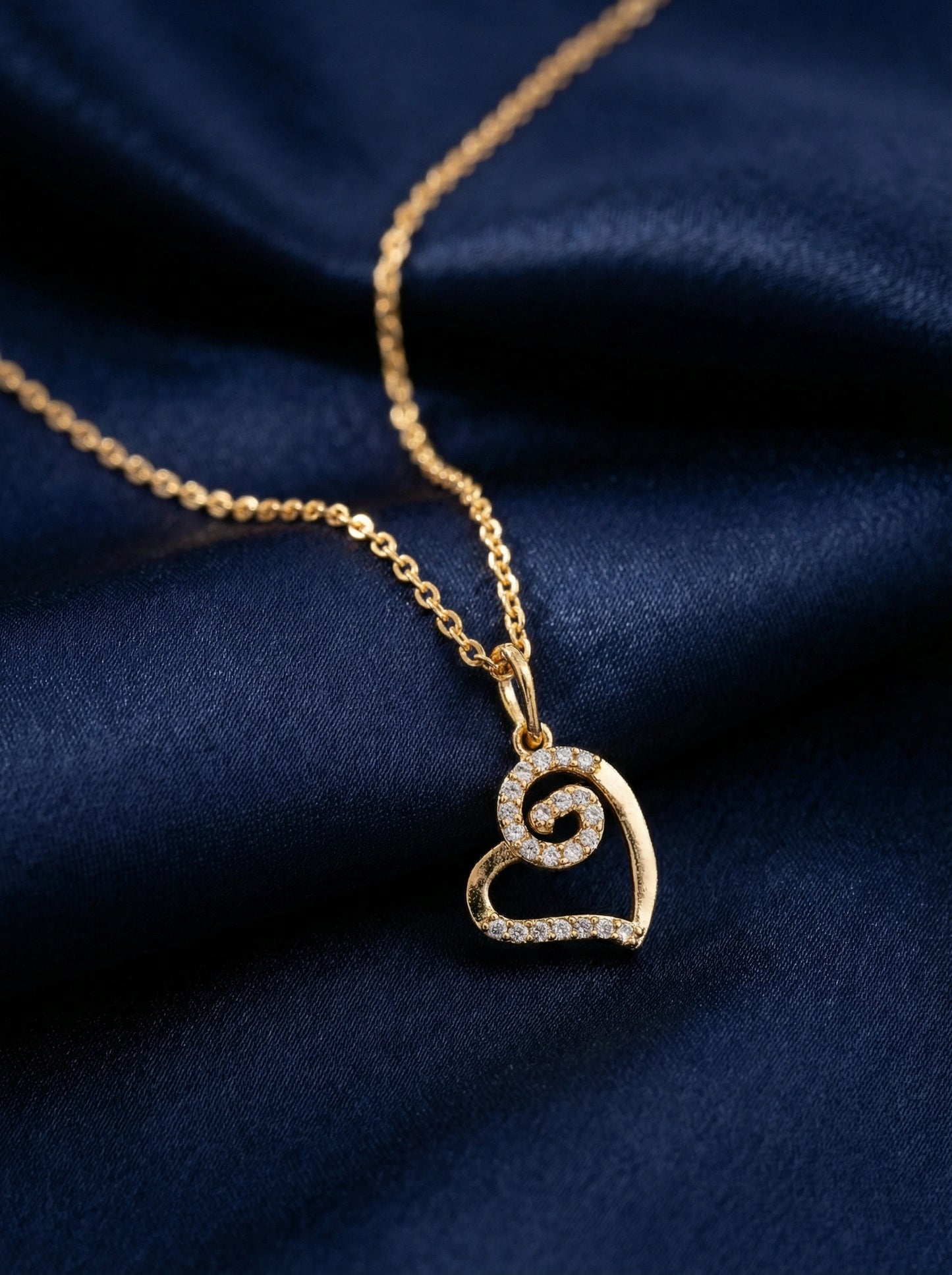 18k gold plated necklace with a heart-shaped pendant on a dark blue fabric background