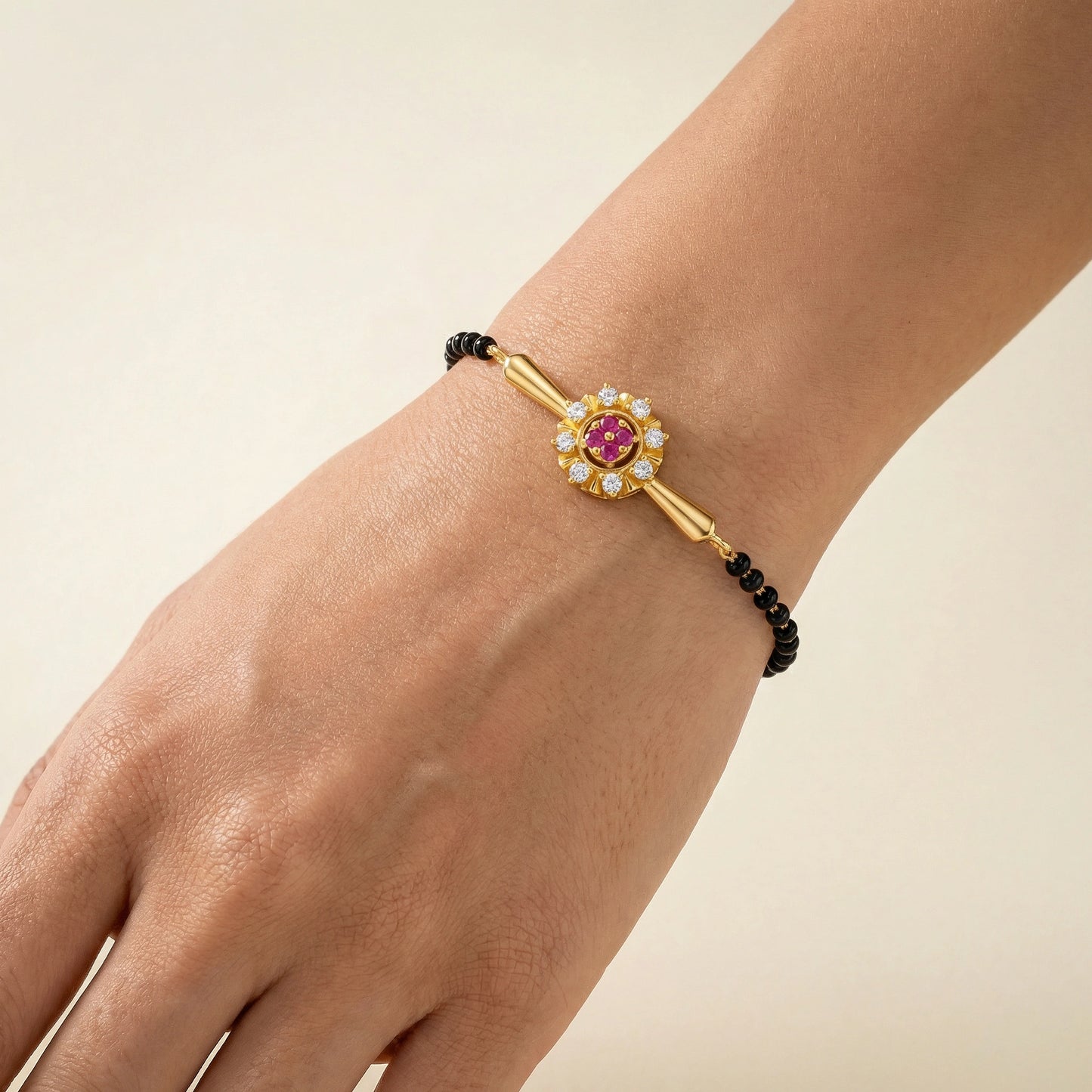 18k gold plated bracelet with a pink gemstone on a wrist against a beige background
