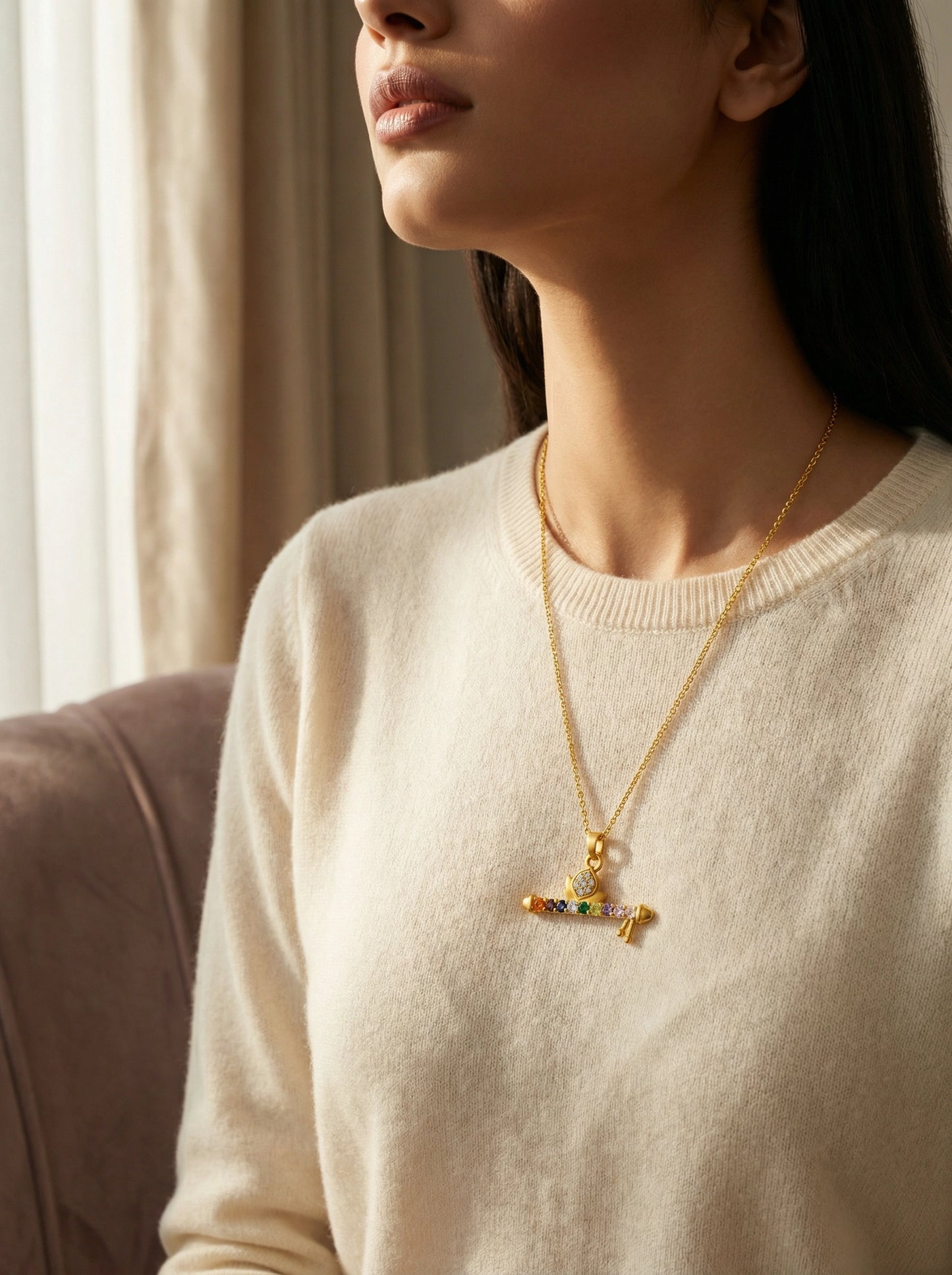 woman wearing a 18k gold plated necklace with a colorful pendant indoors.