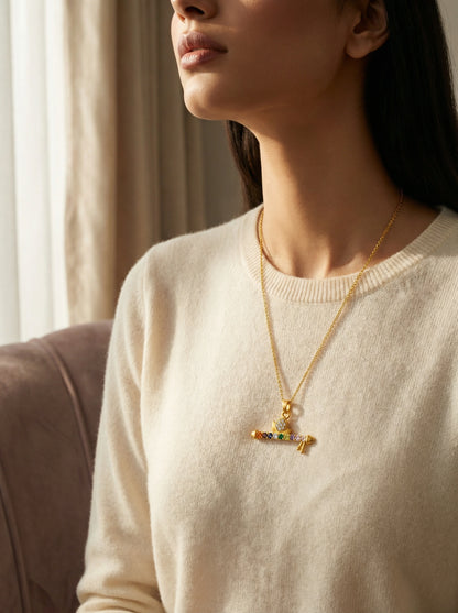 Woman wearing a 18k gold plated necklace with a colorful pendant indoors.