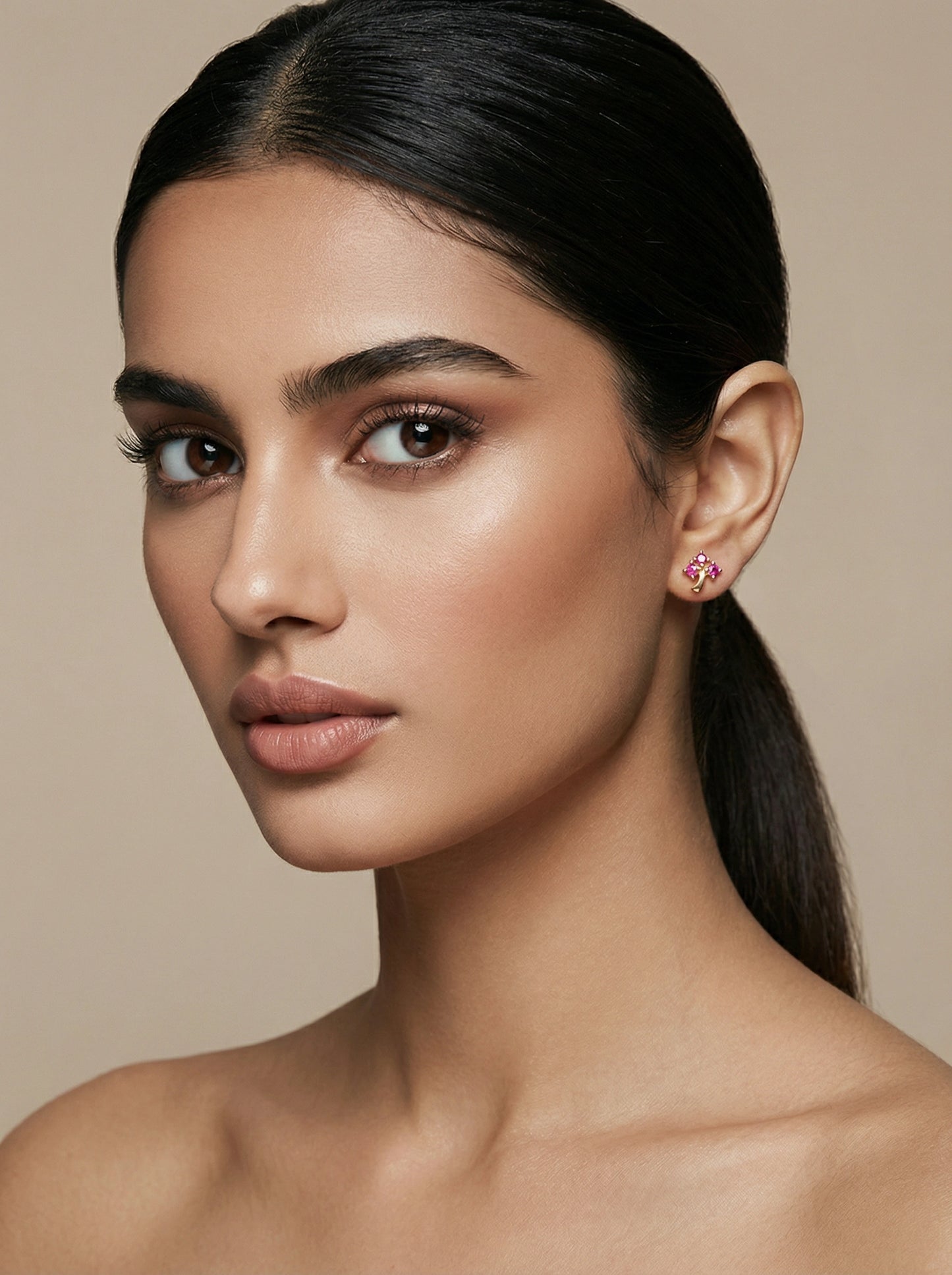 woman wearing pink 18k gold plated earrings against a beige background
