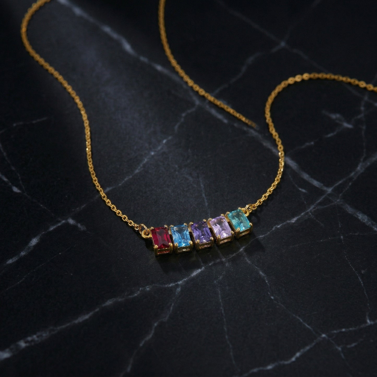 18k gold plated necklace with colorful gemstones on a dark marble surface