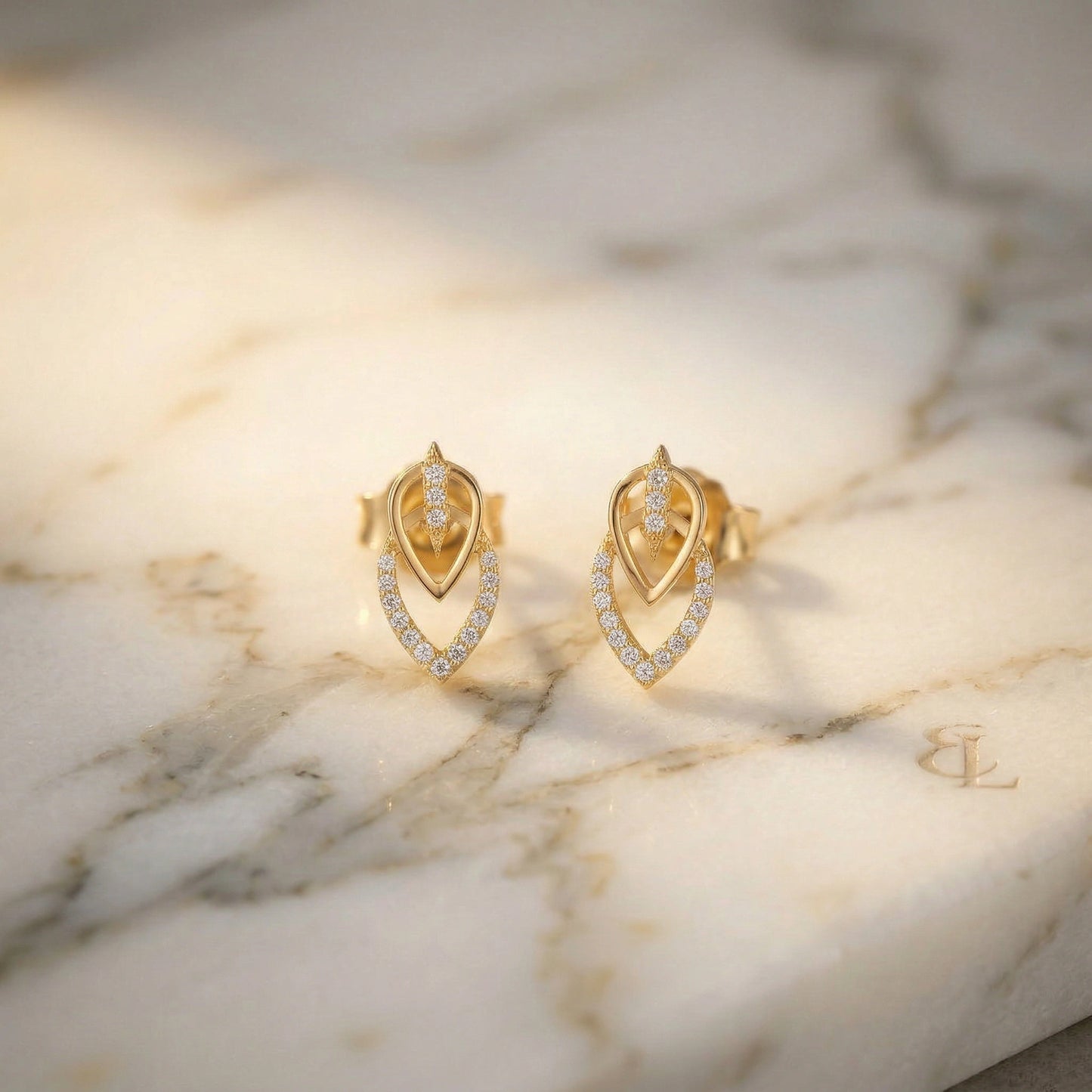 18k gold plated earrings with diamond accents on a marble surface