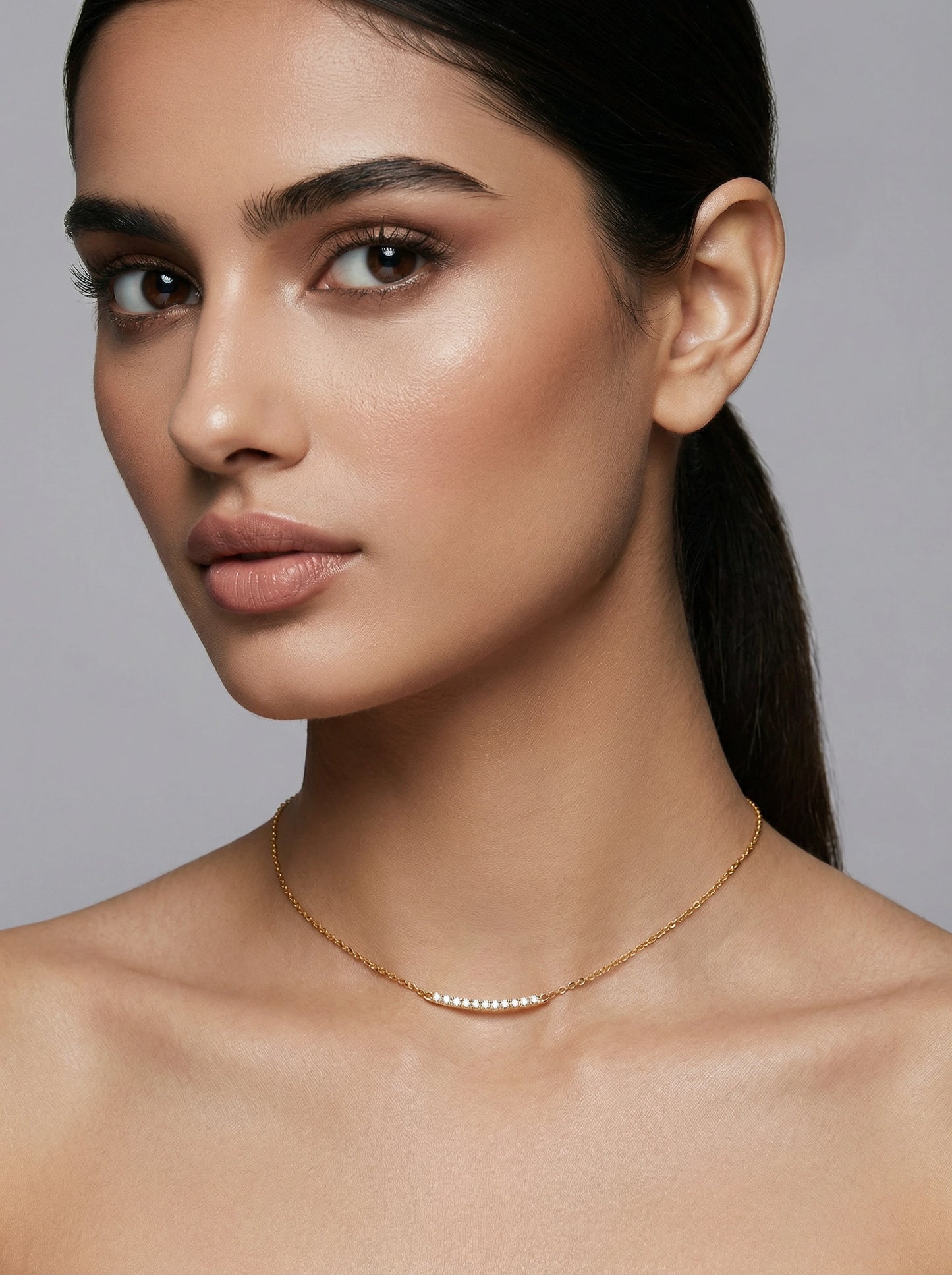 woman wearing a delicate 18k gold plated necklace against a neutral background