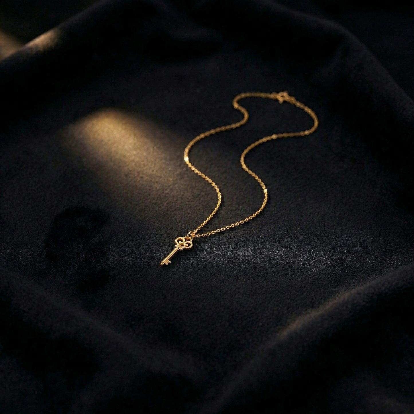 18k gold plated key necklace on a dark fabric background