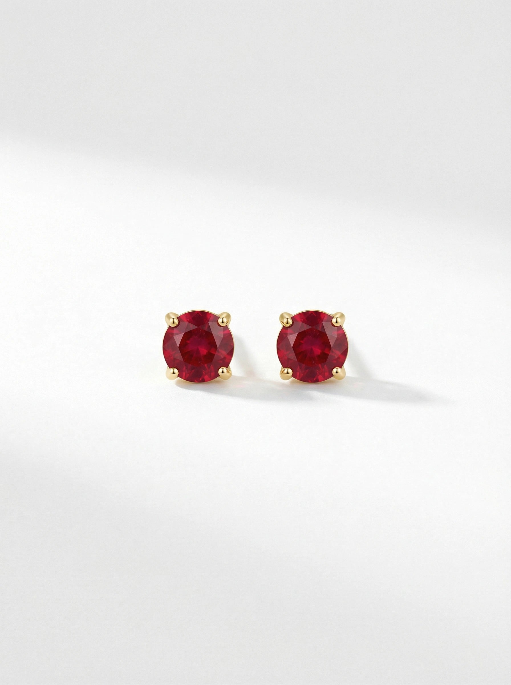Pair of18k gold plated  red gemstone stud earrings on a white background