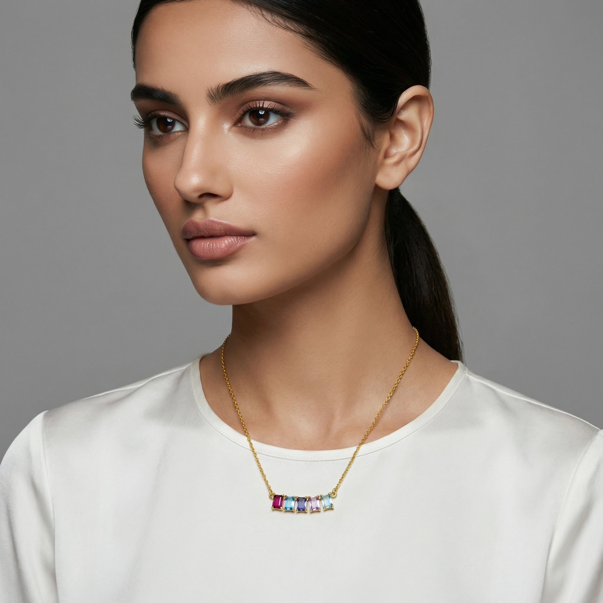 Woman wearing a 18k gold plated necklace with colorful stones against a gray background