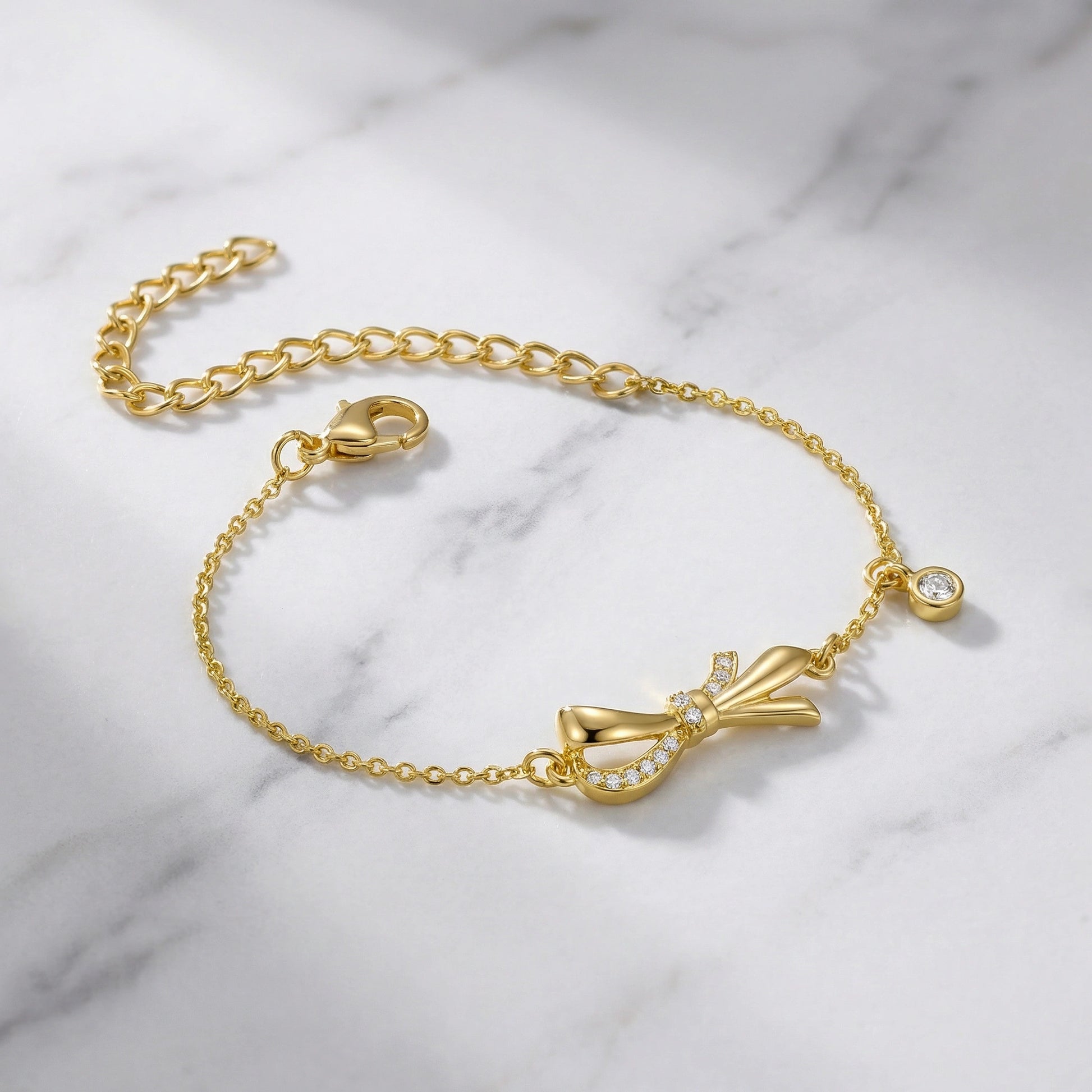 18k Gold plated bracelet with bow charm on a marble background