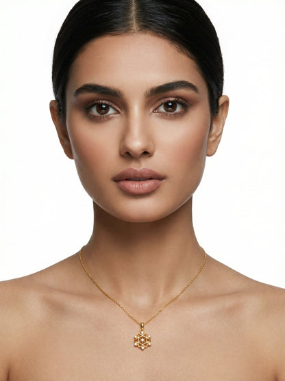 Woman wearing a 18k gold plated necklace with a snowflake pendant on a white background